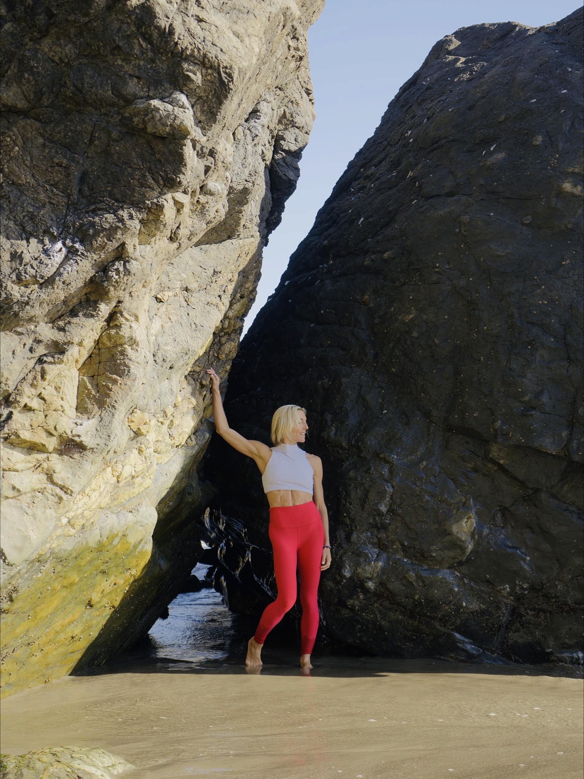 Julie Locke resting a hand against a rock face at the shoreline