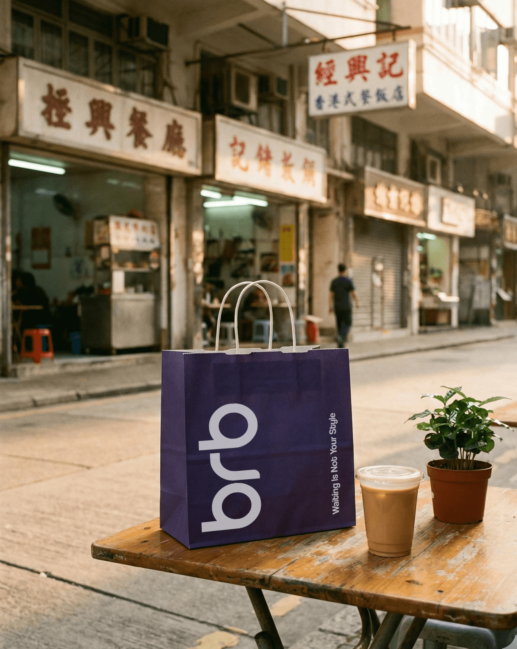 A purple BRB bag placed on a small outdoor table with iced drinks, set in front of traditional Hong Kong shopfronts
