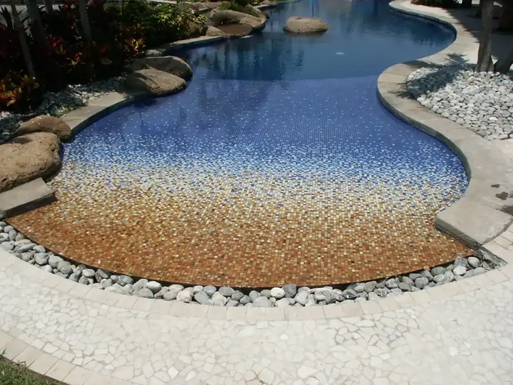Free-form pool with the floor graded from deep blue to sand — Mosaiclegs Art Studio