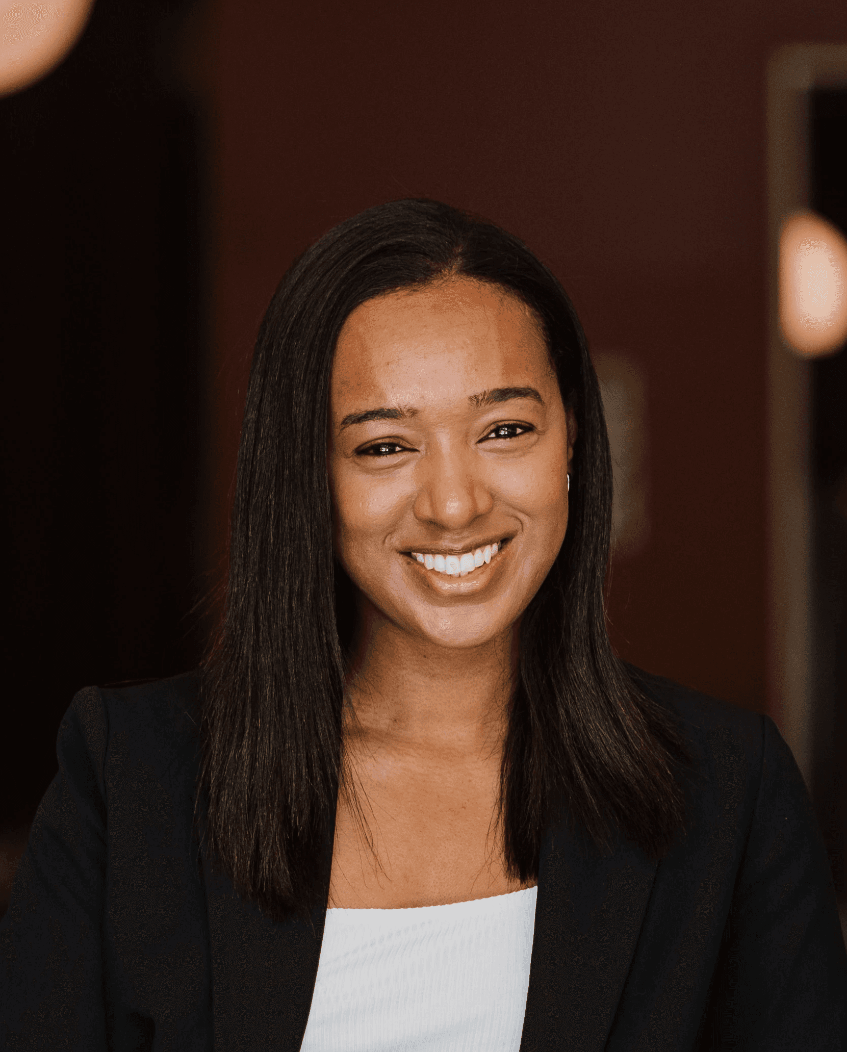 Man with dark hair wearing a black sweater over a collared shirt, softly lit and facing forward