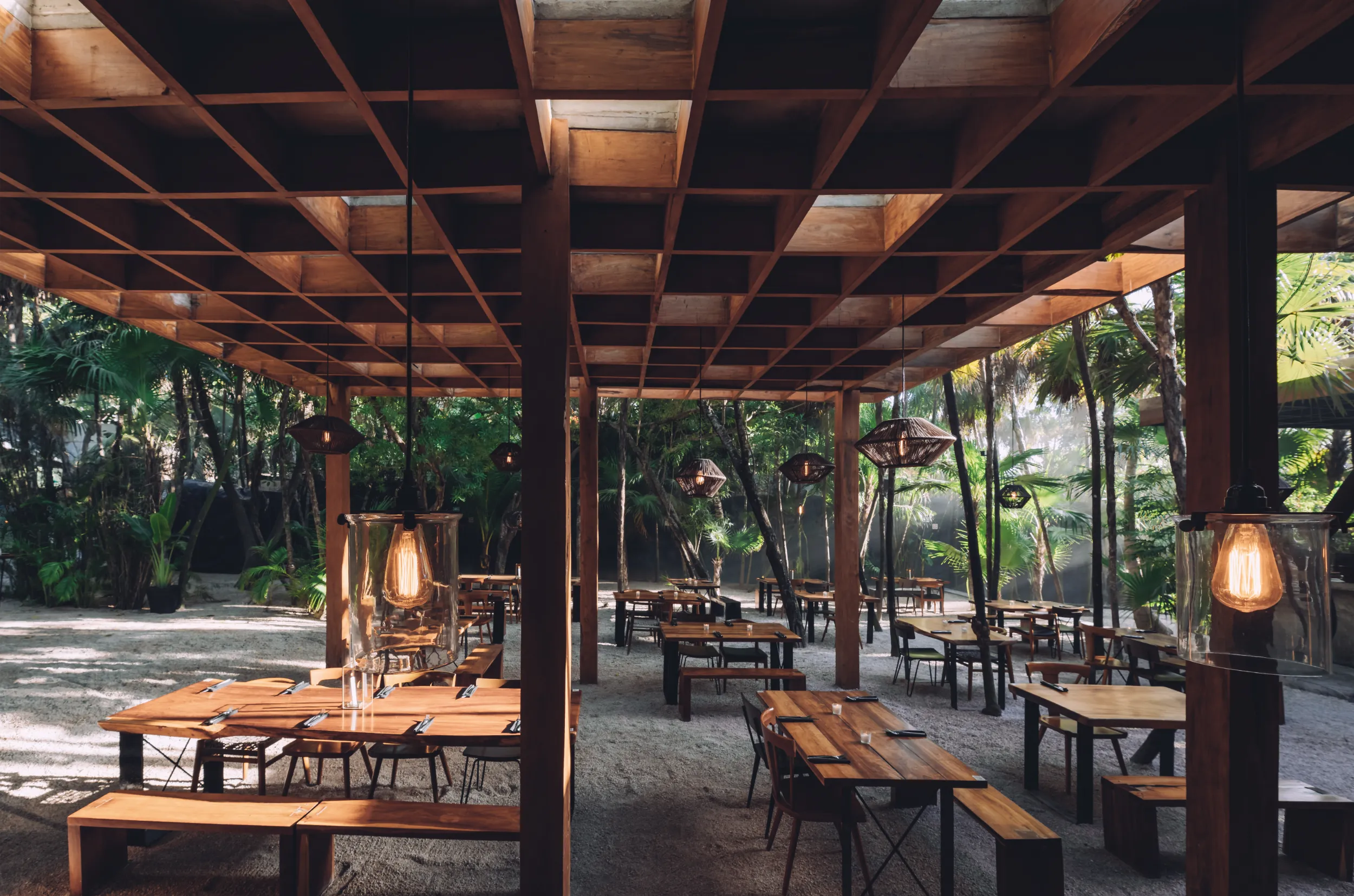 Detail of the wooden reticular ceiling structure (waffle slab) sheltering the open-air dining area with sand floors at Arca Tulum.