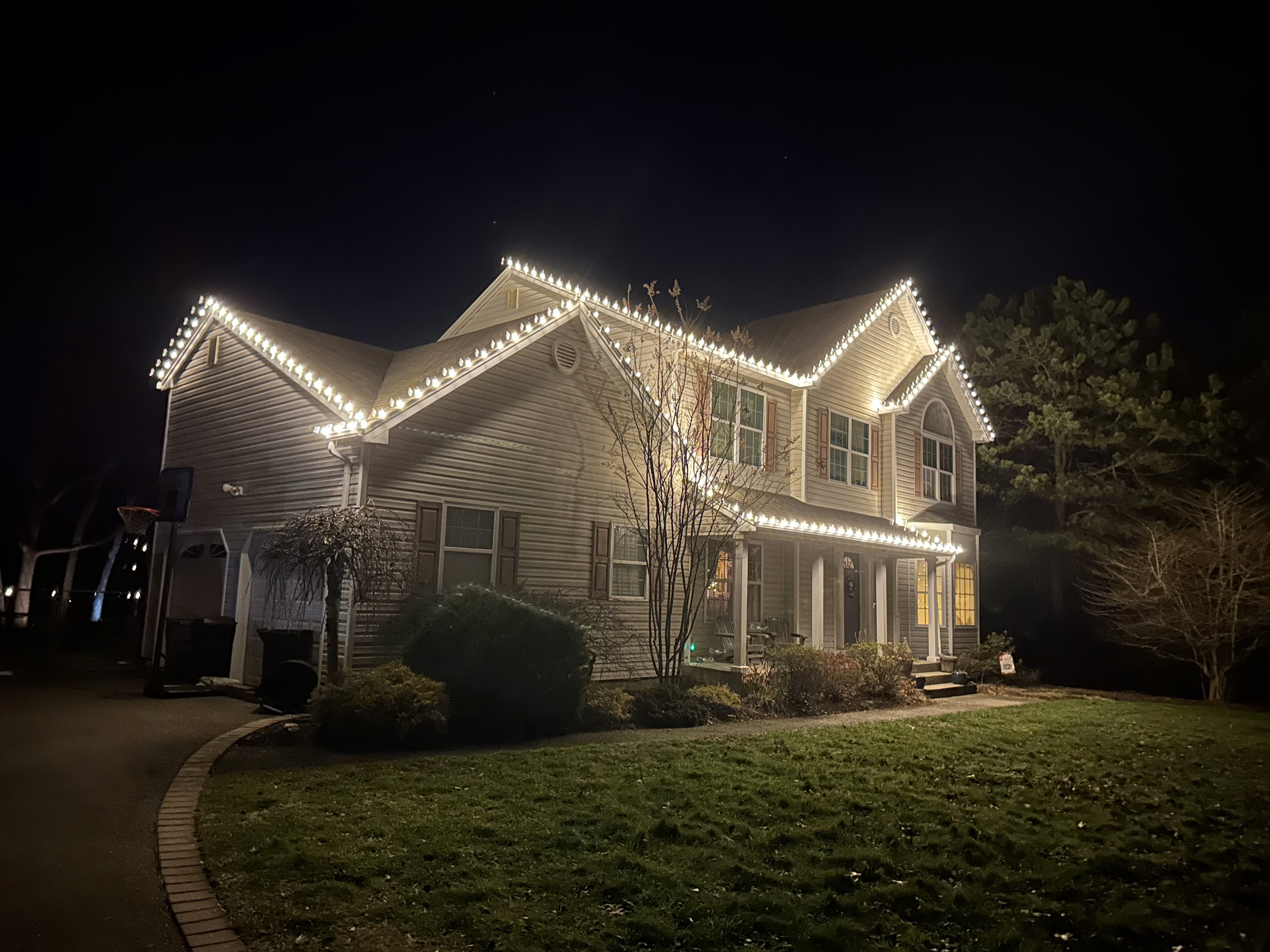 Warm white Christmas lights outlining a luxury home’s peaks and rooflines