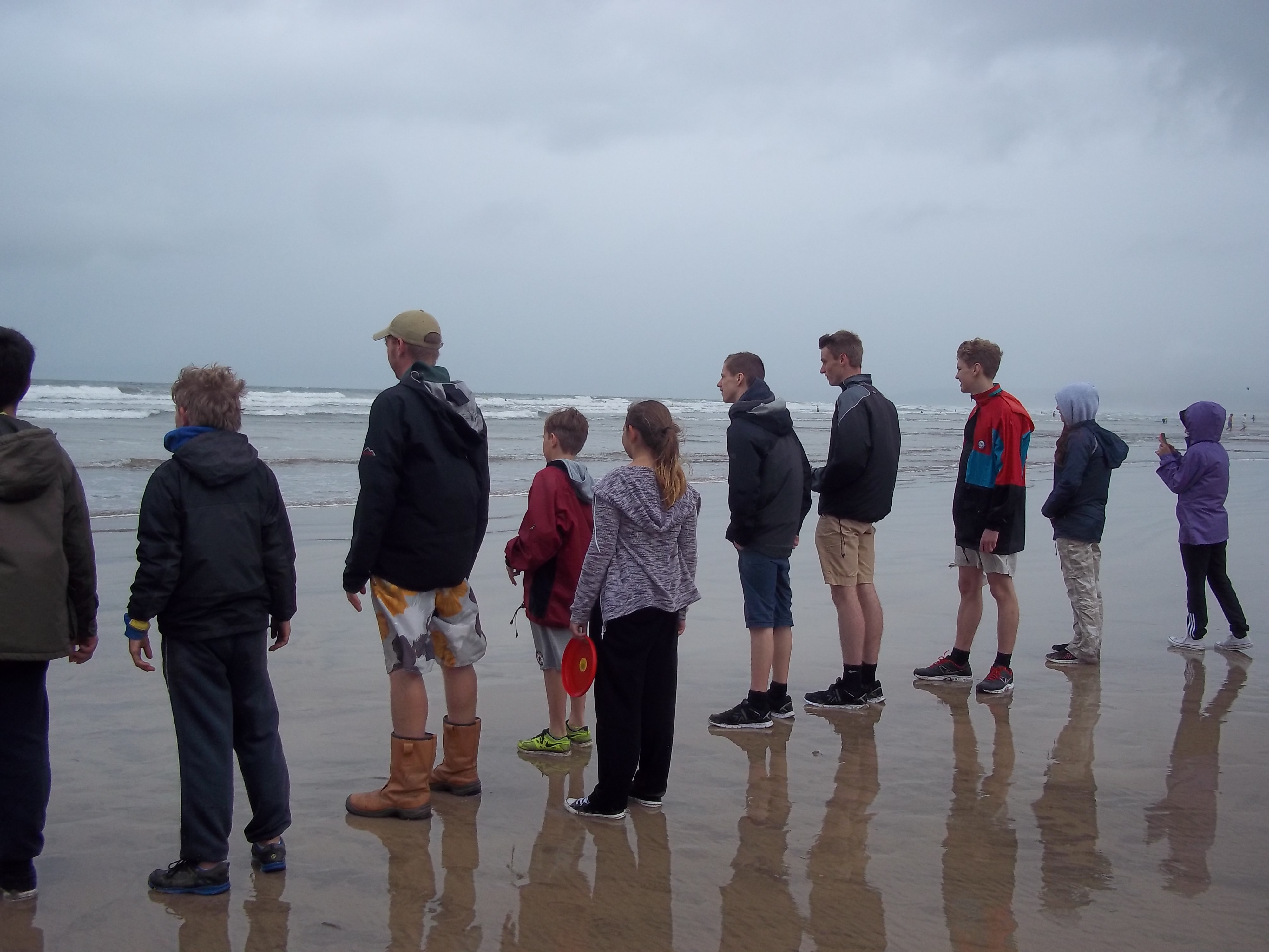 Young people stodd on the beach looking out to sea