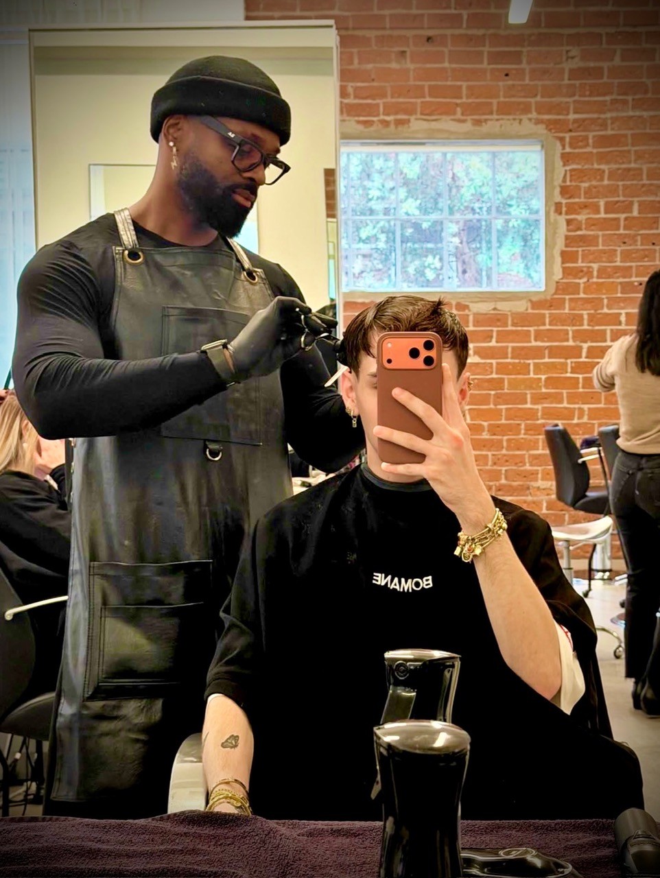 Courtney Palmore, also known as Barber.CLP, sitting confidently in a barber chair, showcasing expertise in luxury barbering and upscale grooming services.