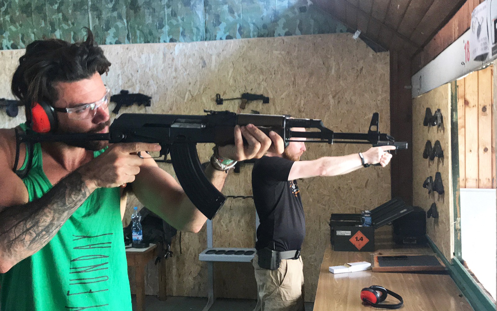 Deelnemers richten geweren op een indoor schietbaan.
