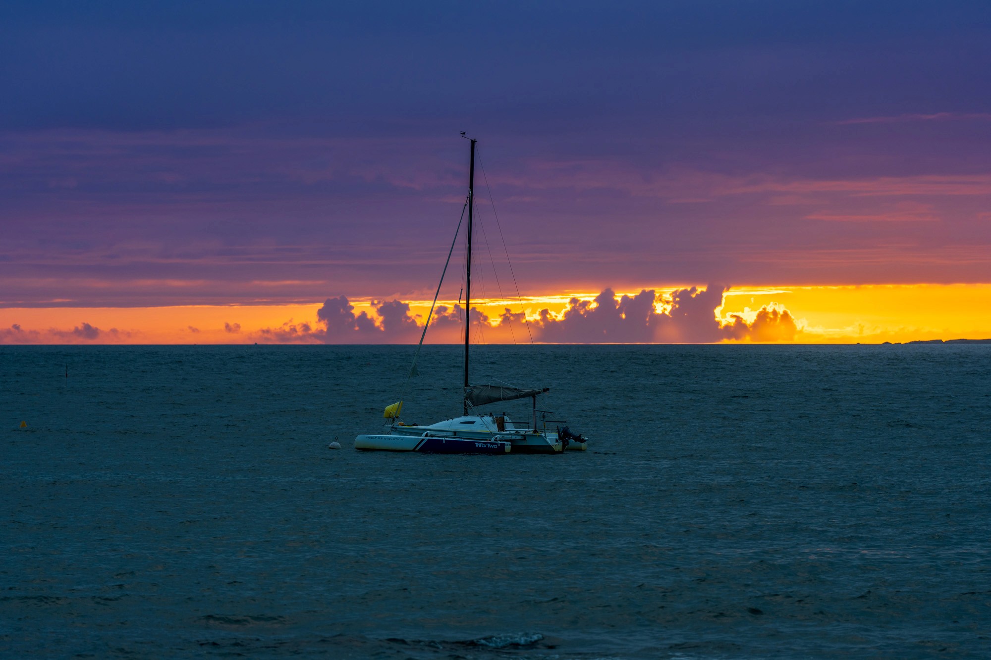 Voilier au mouillage dans un coucher de soleil violet et orange, baie de Piriac