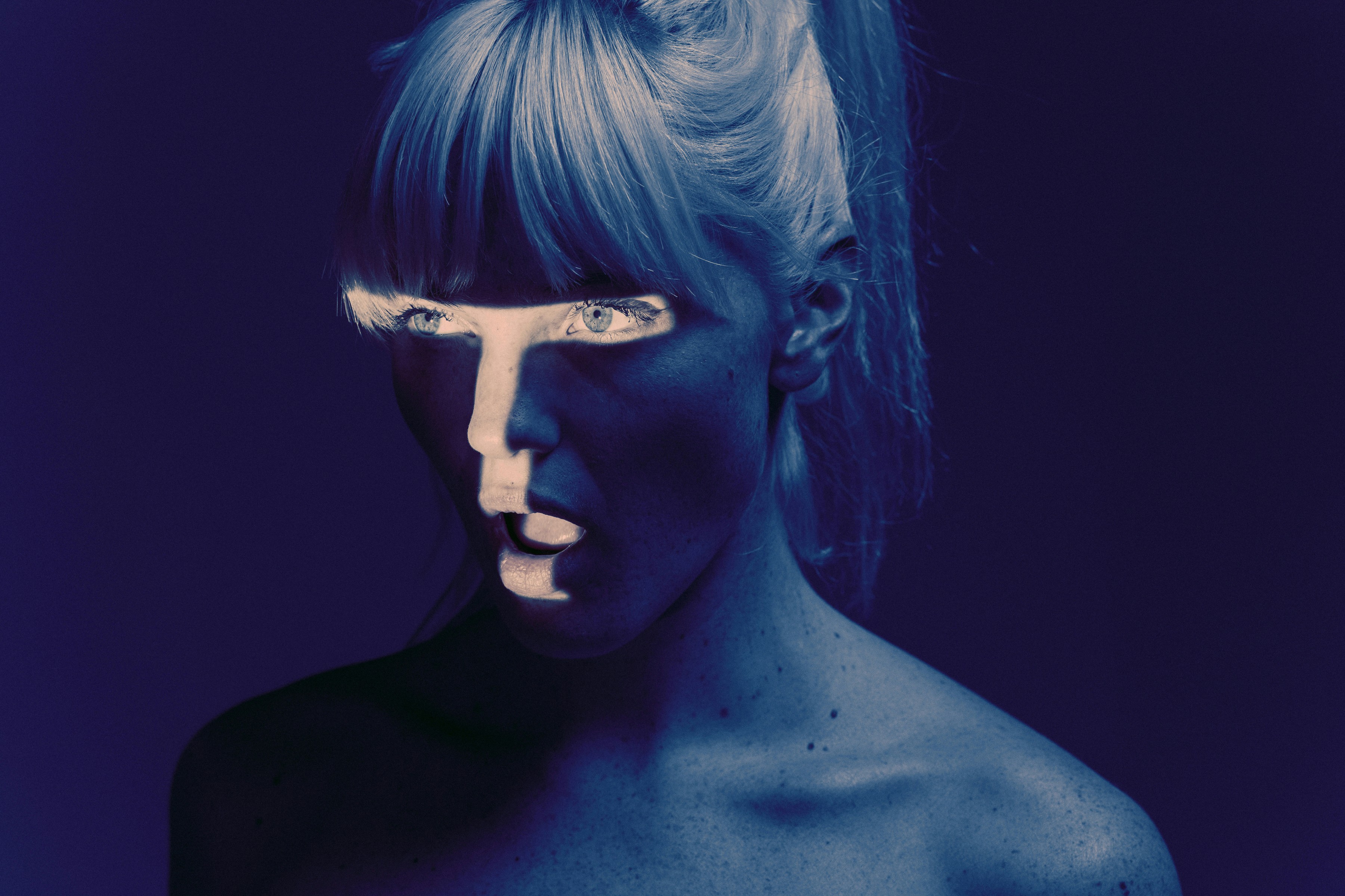 Kontrastreiches Porträt in blauer Lichtstimmung – Sinnbild für menschliche Wahrnehmung im Spannungsfeld von Technologie und Intelligenz.