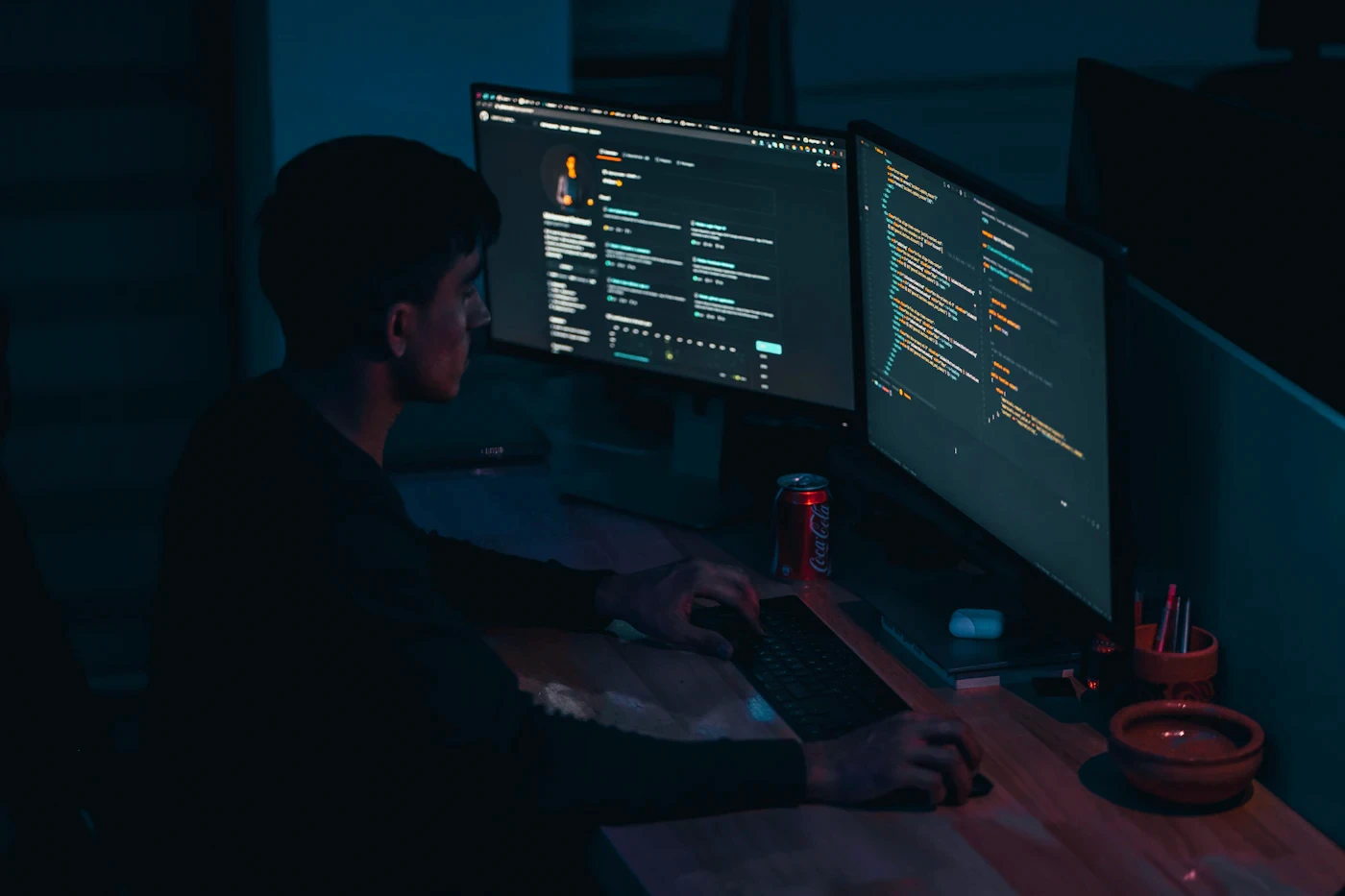 Engineer working with multiple computer displays in a dark office