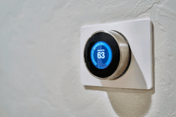 Wall-mounted smart thermostat displaying temperature and energy savings