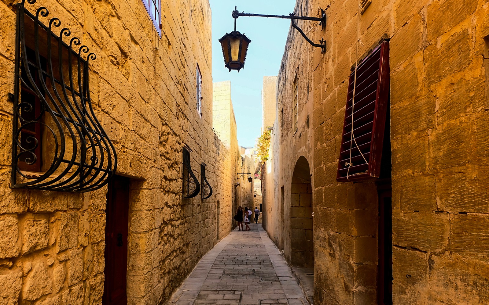 Narrow stone street in Mdina, Malta, with historic architecture and iron window grilles.
