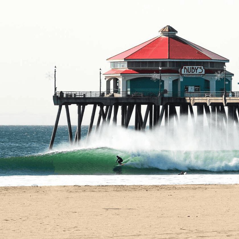 Surfer riding wave near Rube's restaurant – surfboard rental in huntington-beach