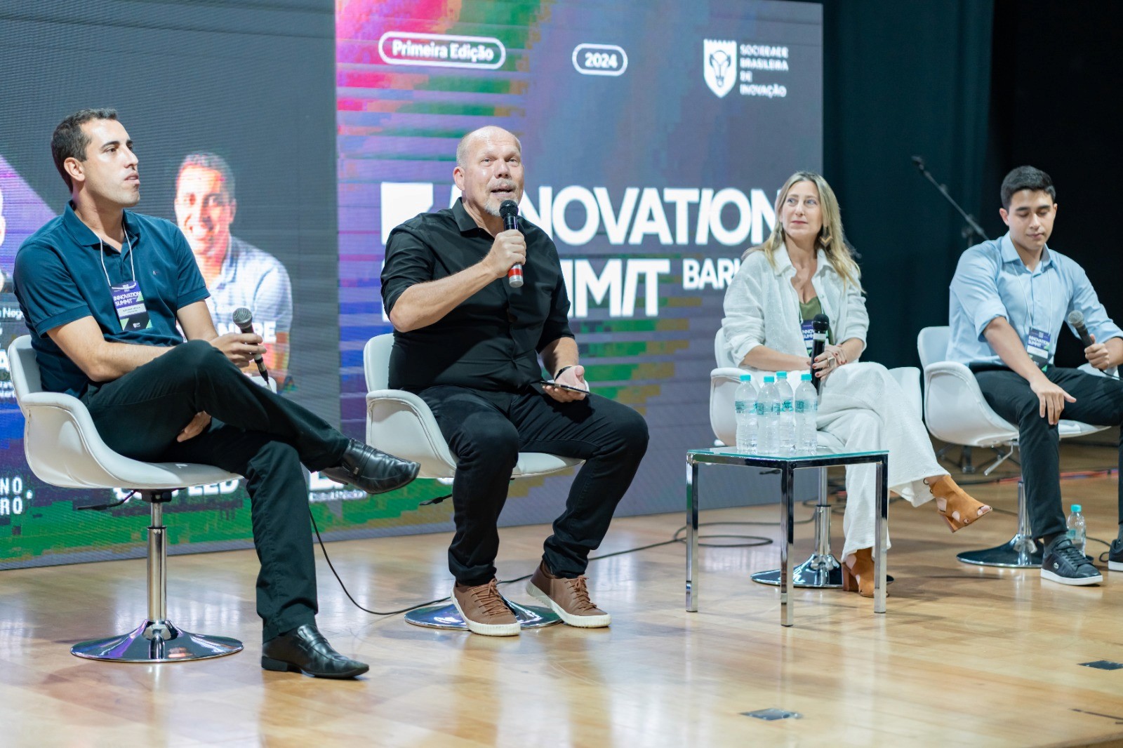 A person attentively paints a vibrant, expressive artwork of two people embracing, featuring bold colors like pink, blue, and green, highlighting themes of love and closeness in the painting.