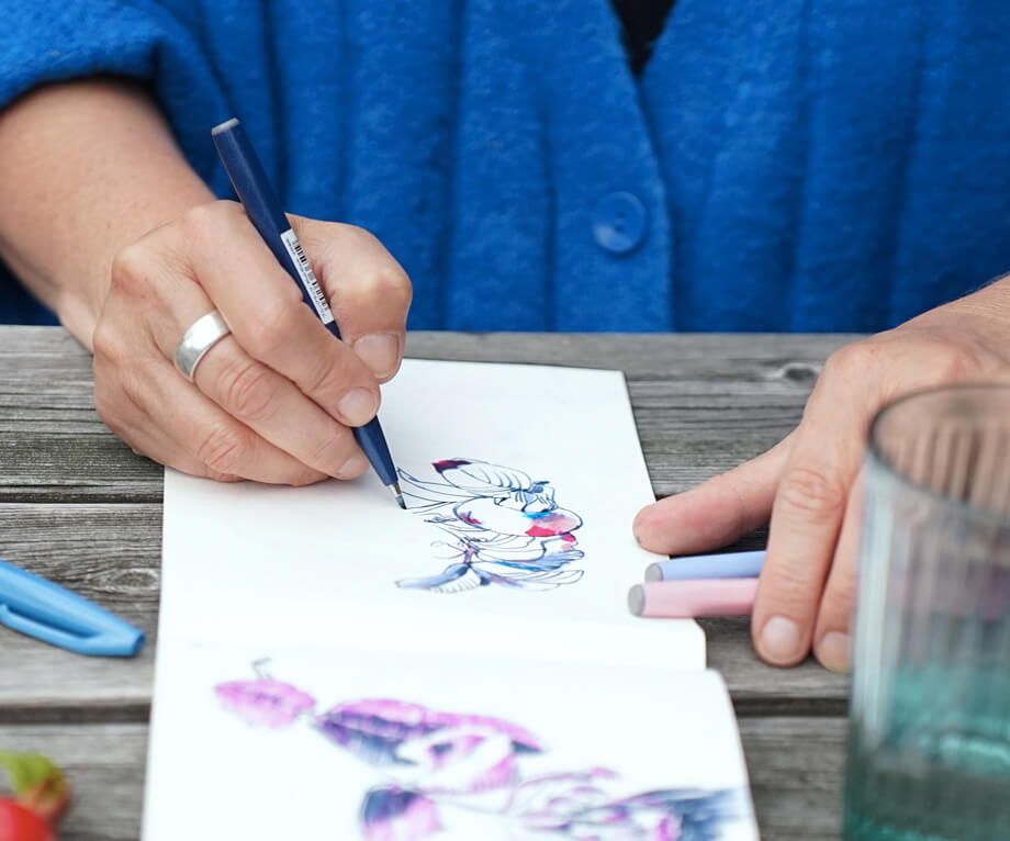 Foto Close Up einer Hand, die in ein Skizzenbuch zeichnet