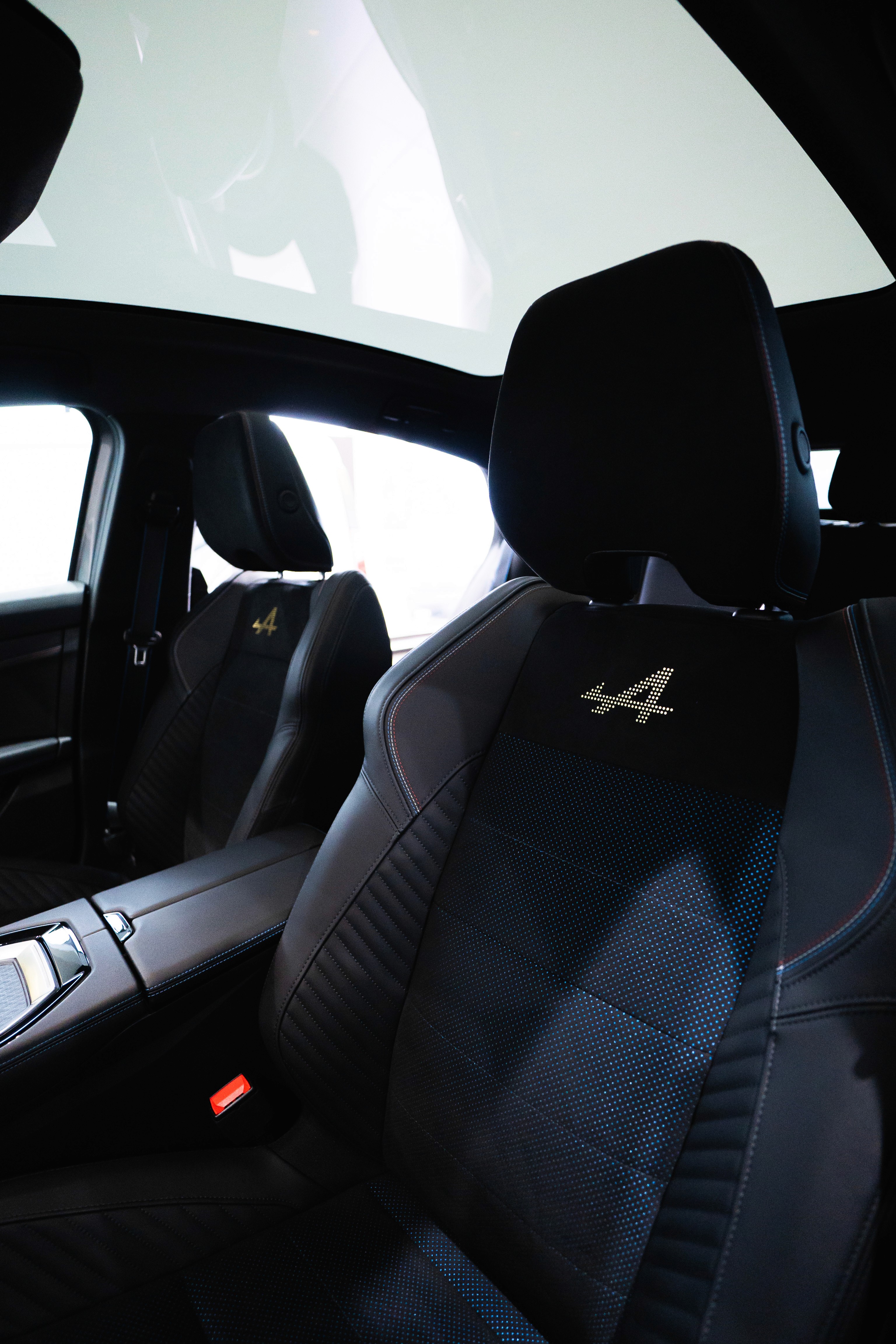 A woman wearing a shiny coat stands in focus, while a blurred background creates a sense of movement.