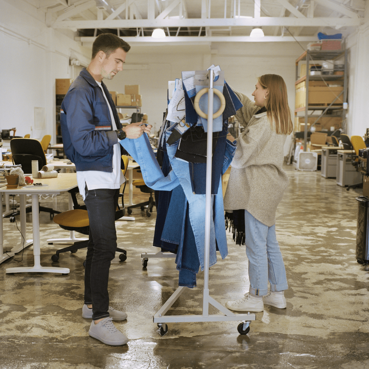 Two people in front of a rack of jeans working together.