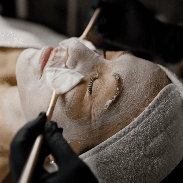 Smiling woman with a dab of moisturizer on her nose, eyes closed, enjoying her skincare routine