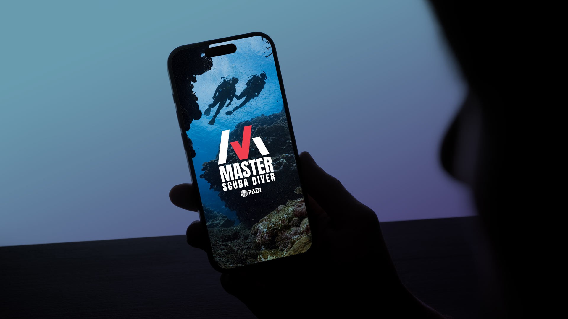 Lifestyle mockup of a mobile Master Scuba Diver campaign asset featuring underwater divers, ocean imagery, and bold achievement-focused branding displayed on a smartphone screen.