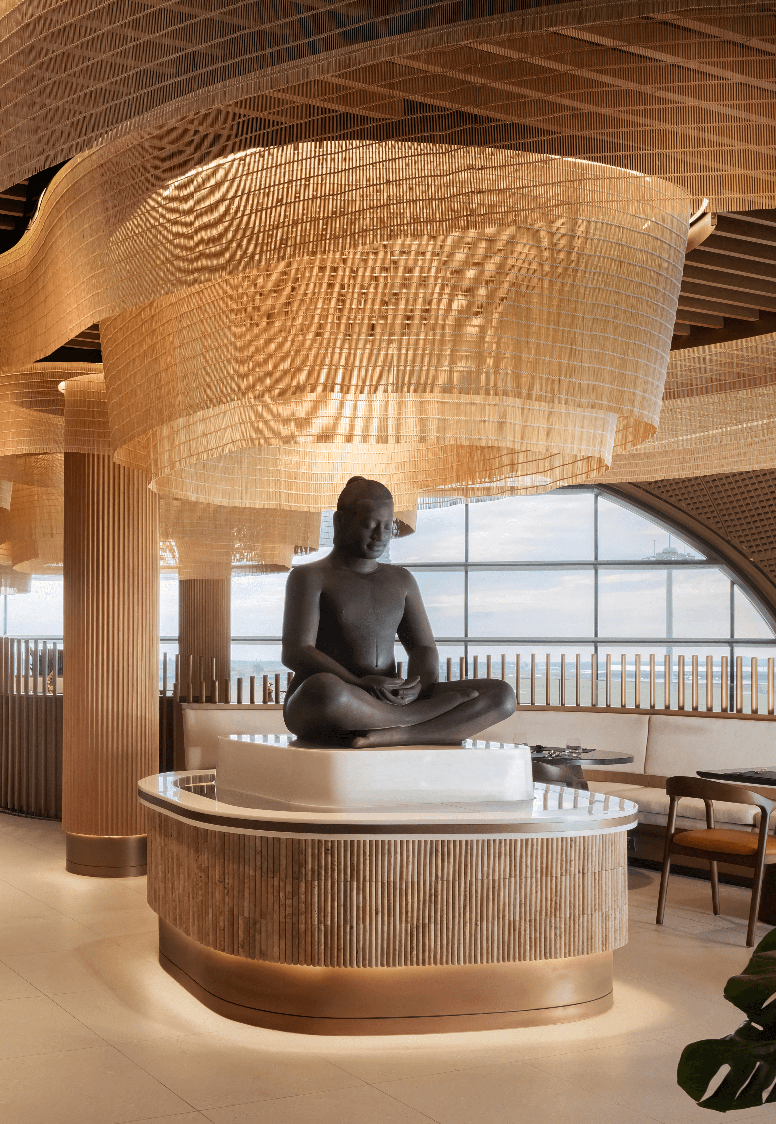 buddha-statue-restaurant-interior-focal A large Buddha statue set beneath a golden silk light installation in the Malis Restaurant at Techo Airport.
