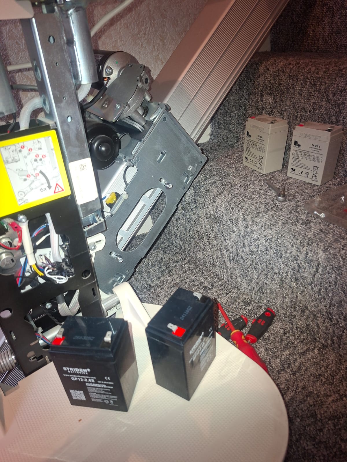 Stairlift engineer servicing the internal drive mechanism and replacing the backup batteries on a domestic stairlift