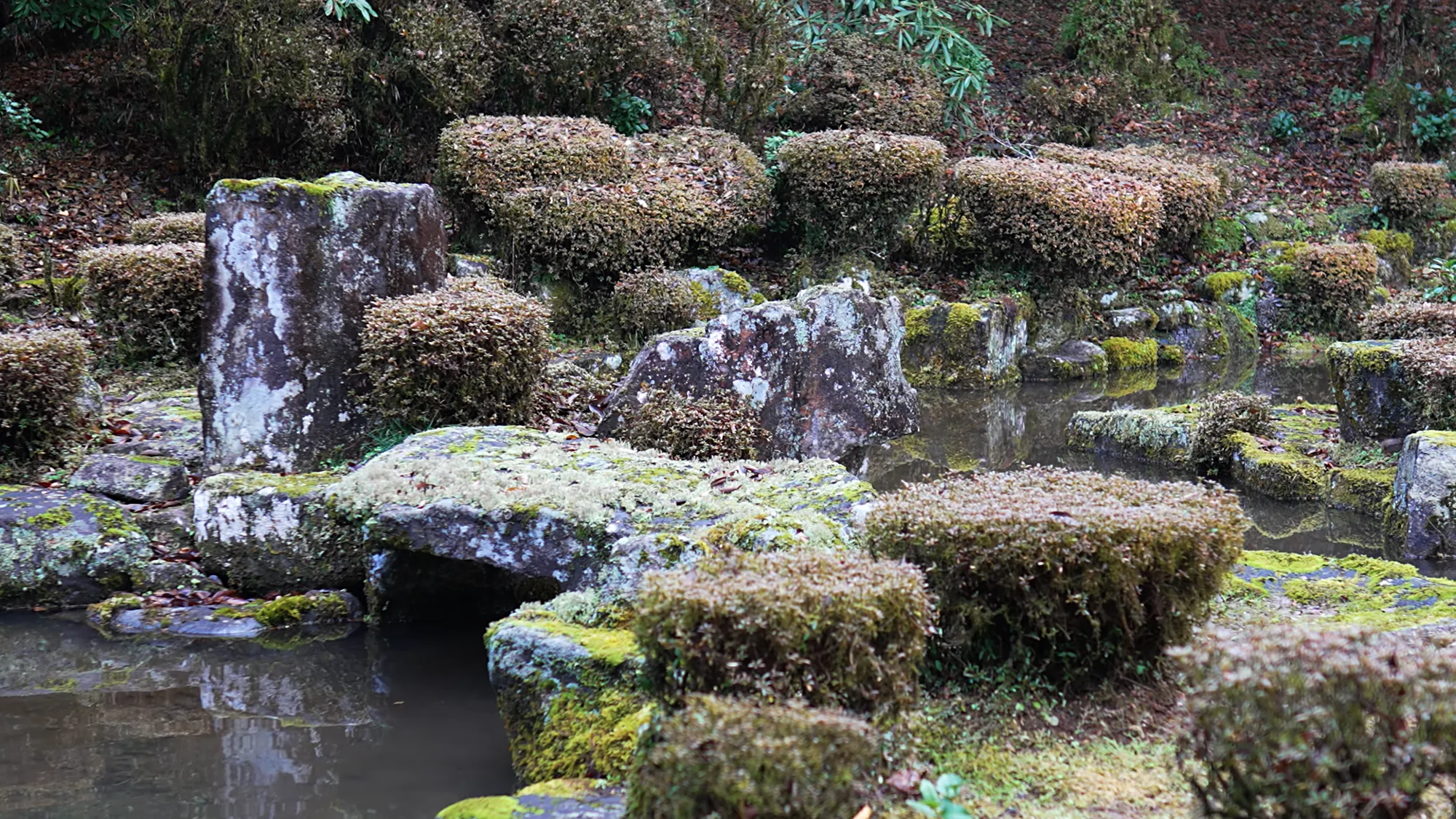 Mossy stone terraces beside running water at Kurokawa Onsen