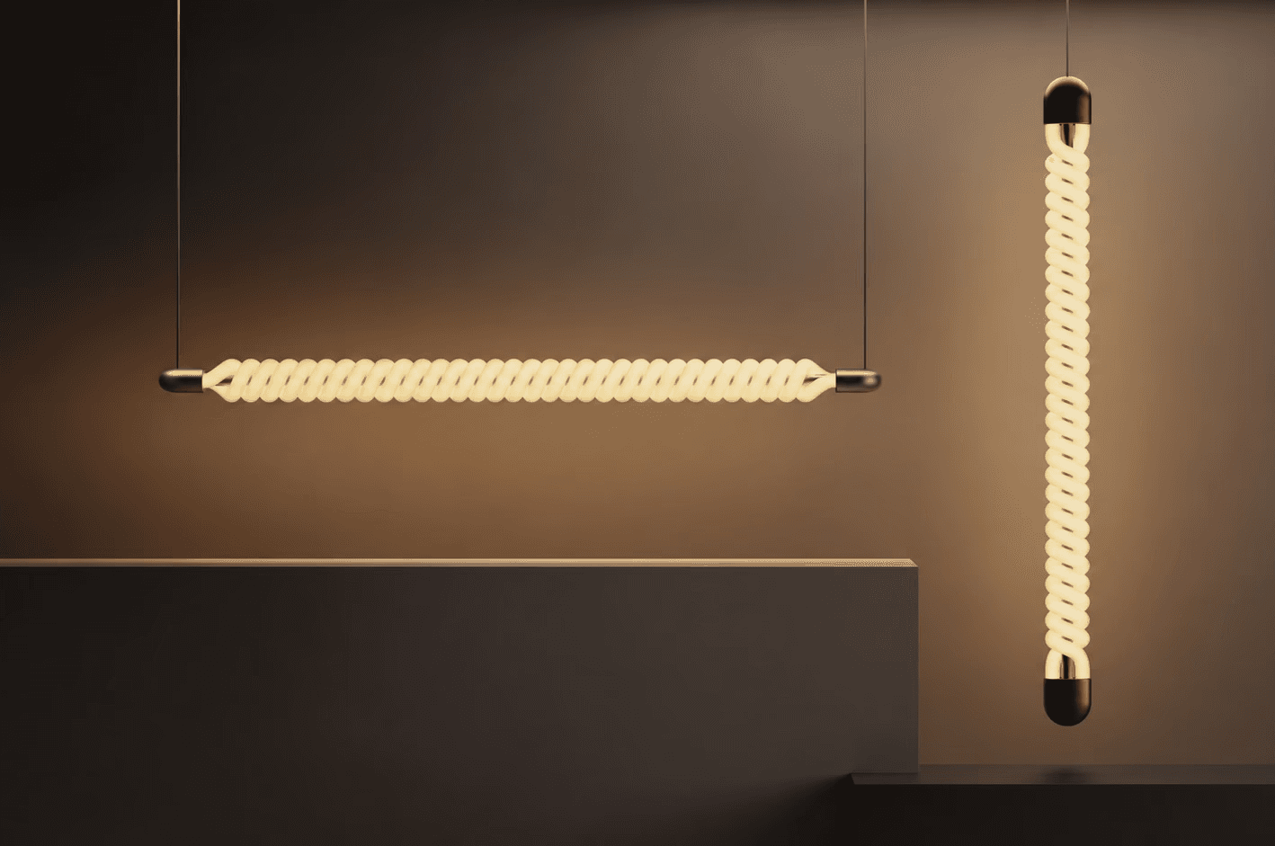 Two glowing pendant lights made of twisted tubes, one hanging horizontally and one vertically, against a warm brown wall