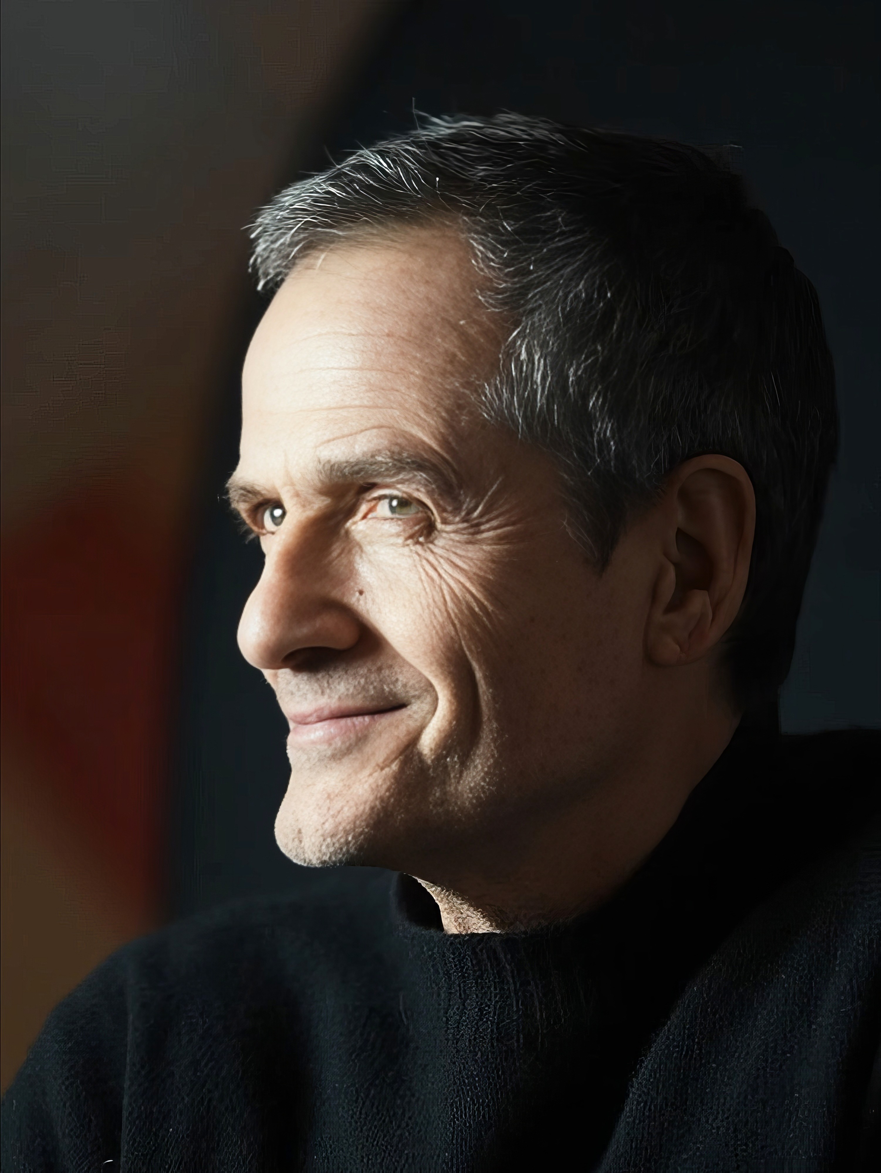 Bride sitting on ground against wall, groom standing nearby
