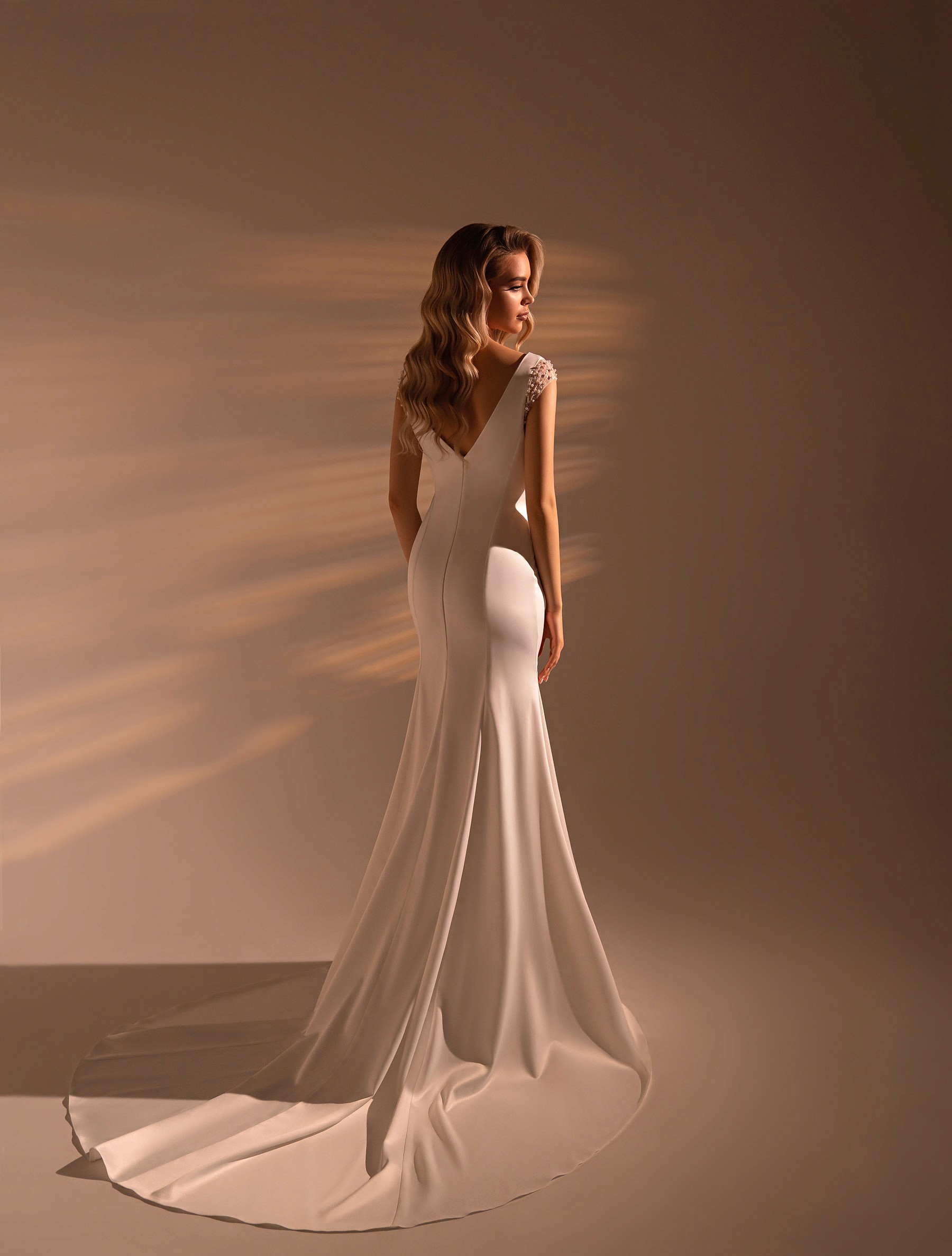 Achteraanzicht van een minimalistische trouwjurk met lage rug en lange sleep