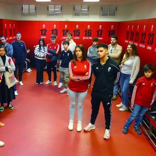 Skupina ljudi u ležernoj sportskoj odjeći stoji u crvenoj prostoriji s numeriranim ormarićima. Dvije su osobe u središtu prvog plana.