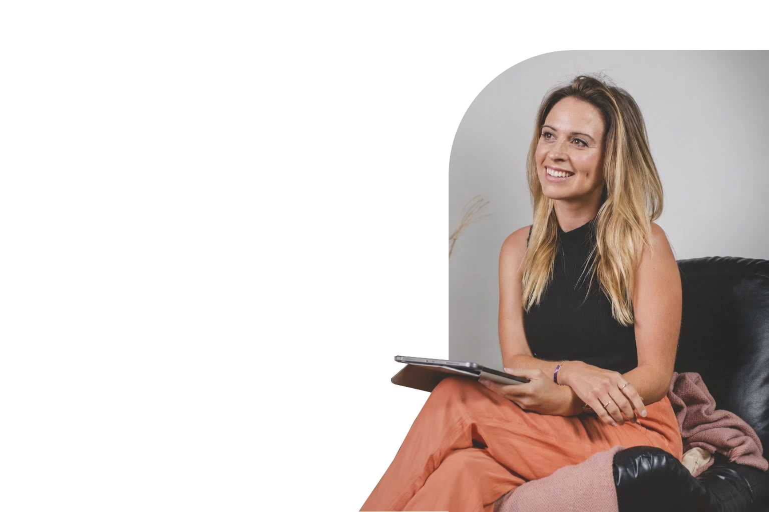 Smiling psychotherapist seated with a tablet in a bright, welcoming therapy setting.