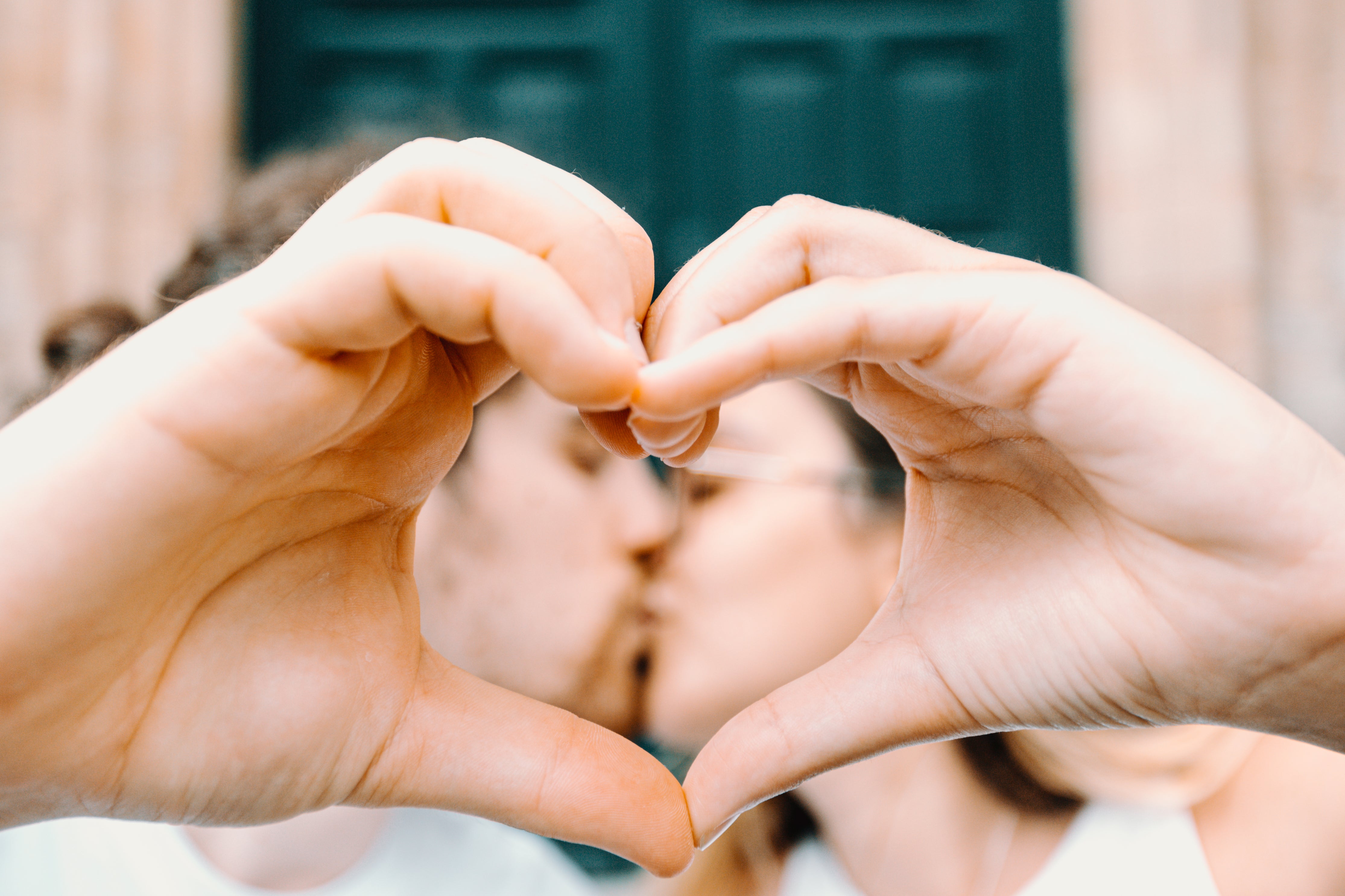 hand meet to form a heart and frame kissing couple
