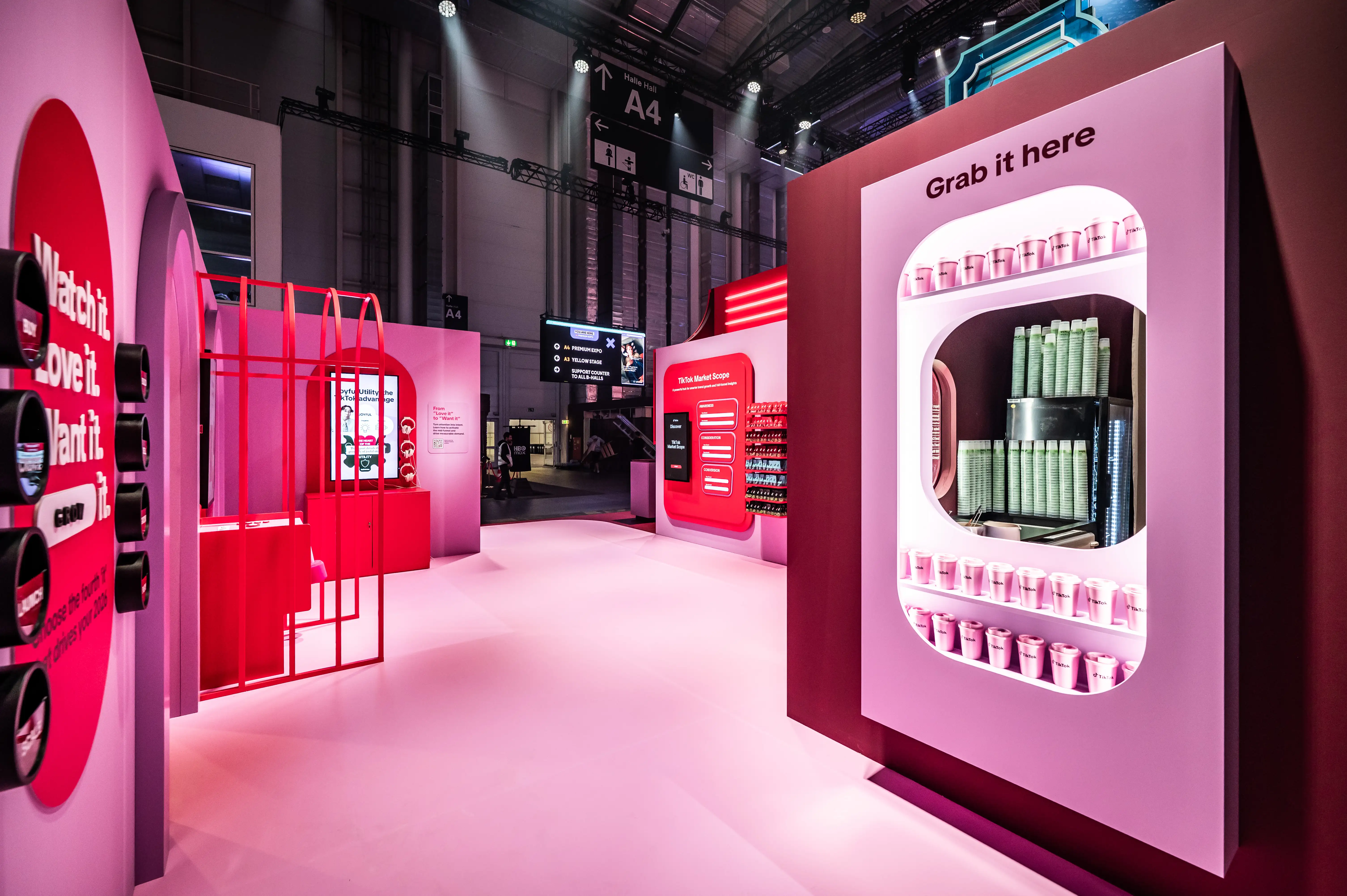 Pink shopping zone with Grab it here product wall, red display cage and round slogan panels.