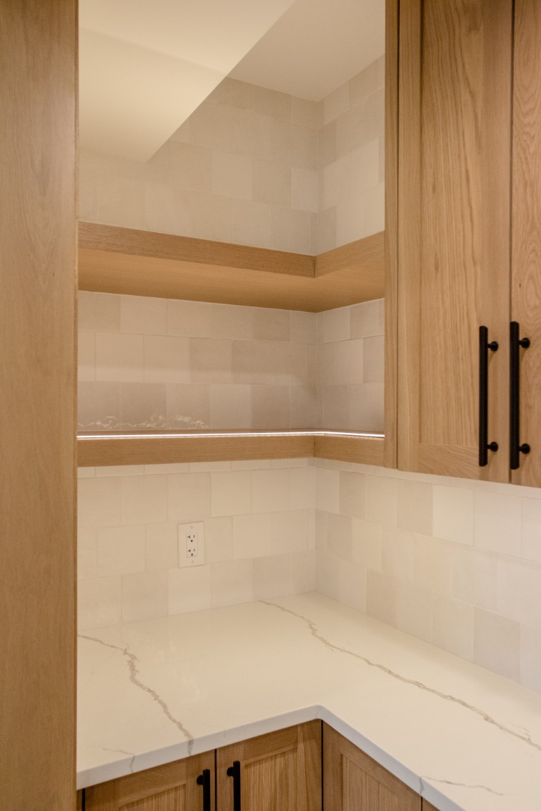 Image of Luxury kitchen interior with marble countertops, wooden cabinets, and tile backsplash designed by KHD Homes.