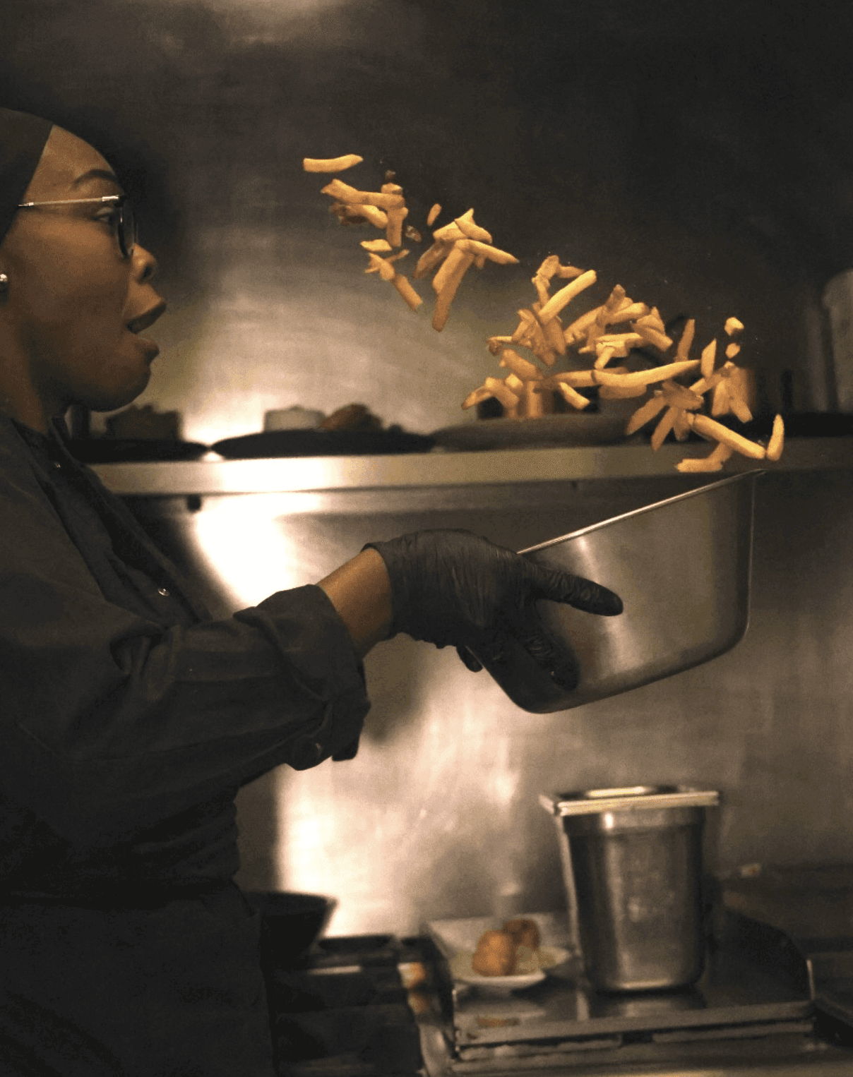Restaurant interior with wooden tables and chairs lined against a textured wall, softly lit by round wall lamps.