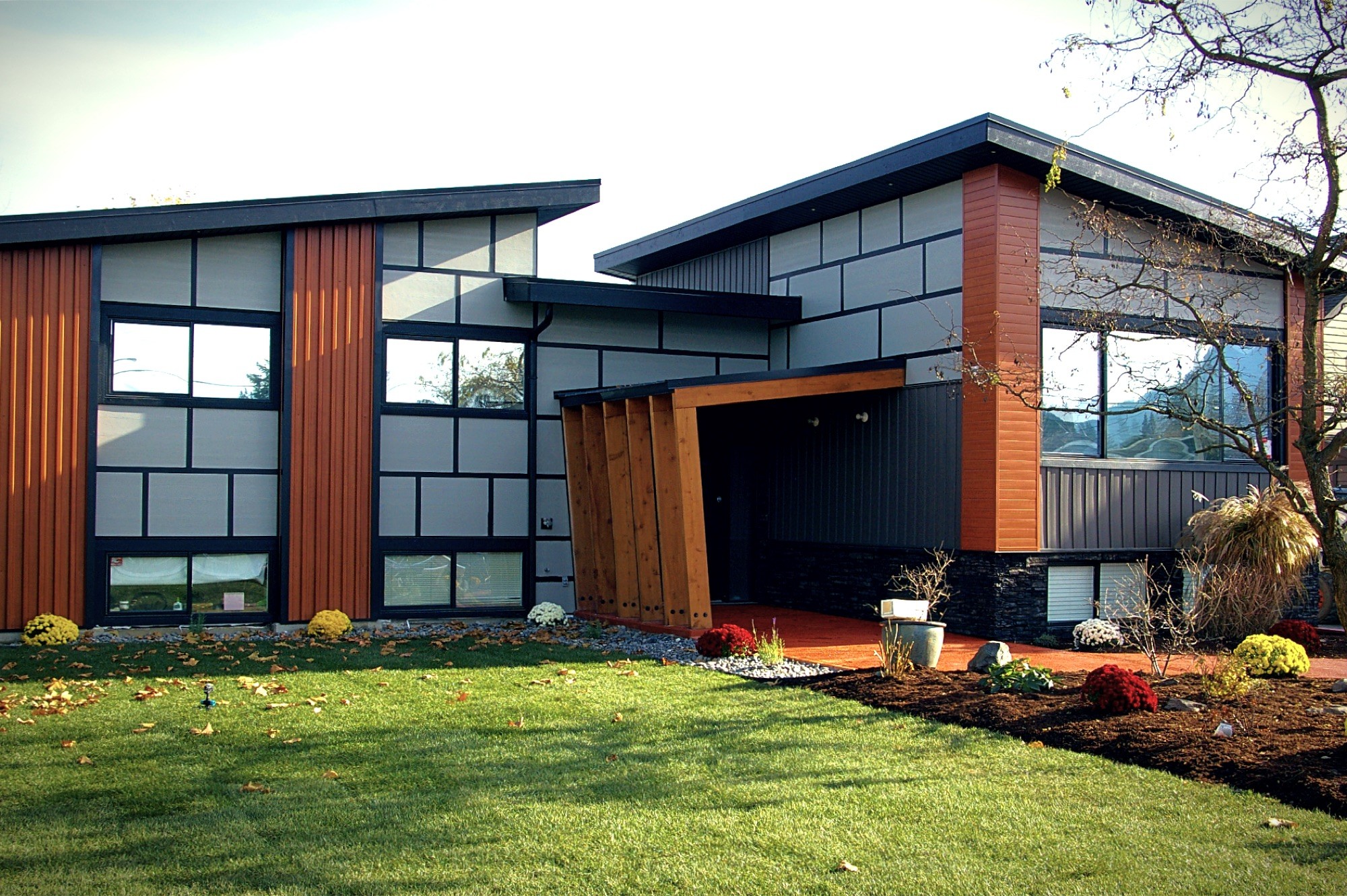 Front elevation of the Miller Renovation with cedar and charcoal panel cladding, stone base and wide glazing