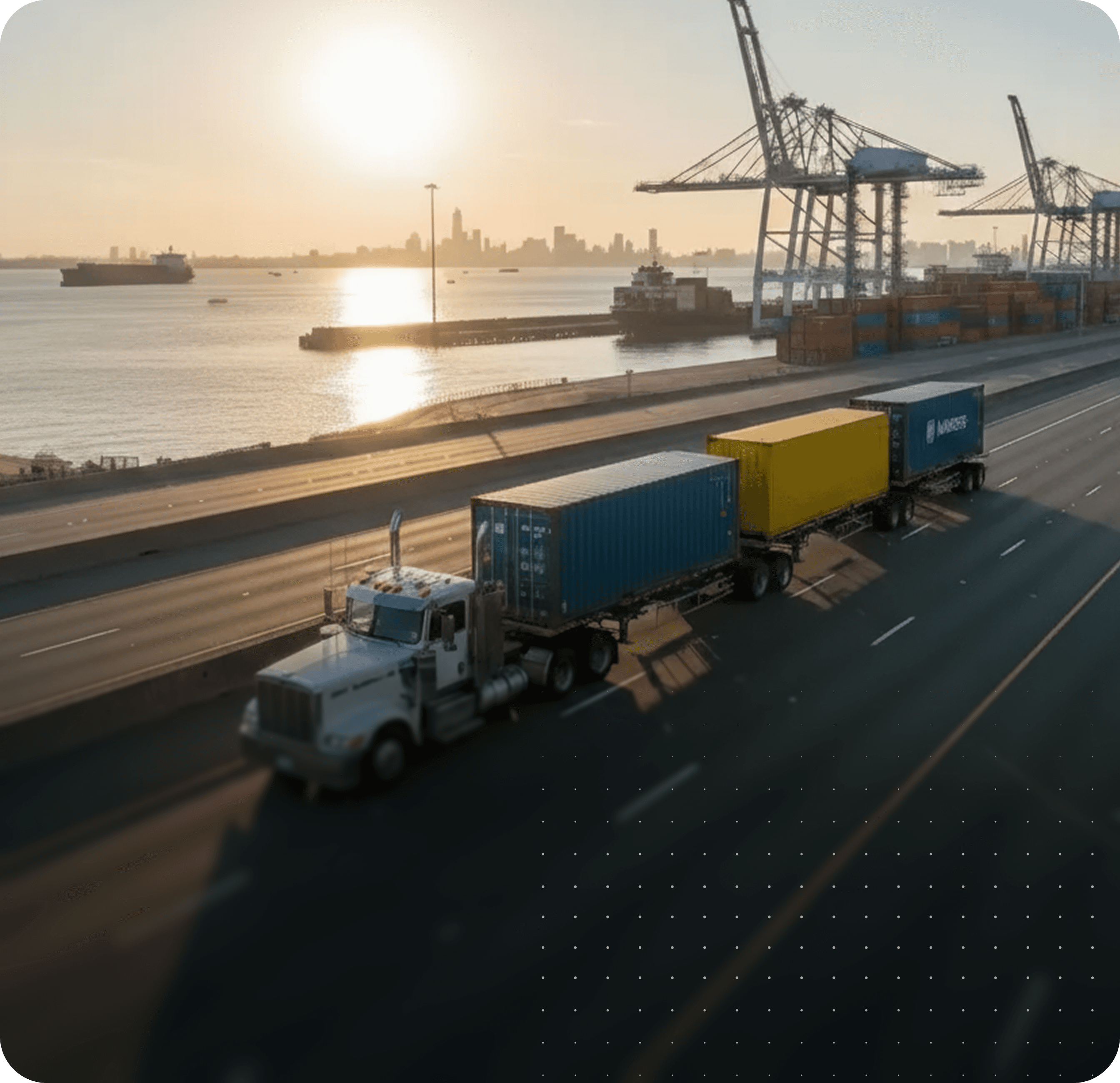 Aerial view of trucks by a port during sunrise, with cranes and containers in the background.