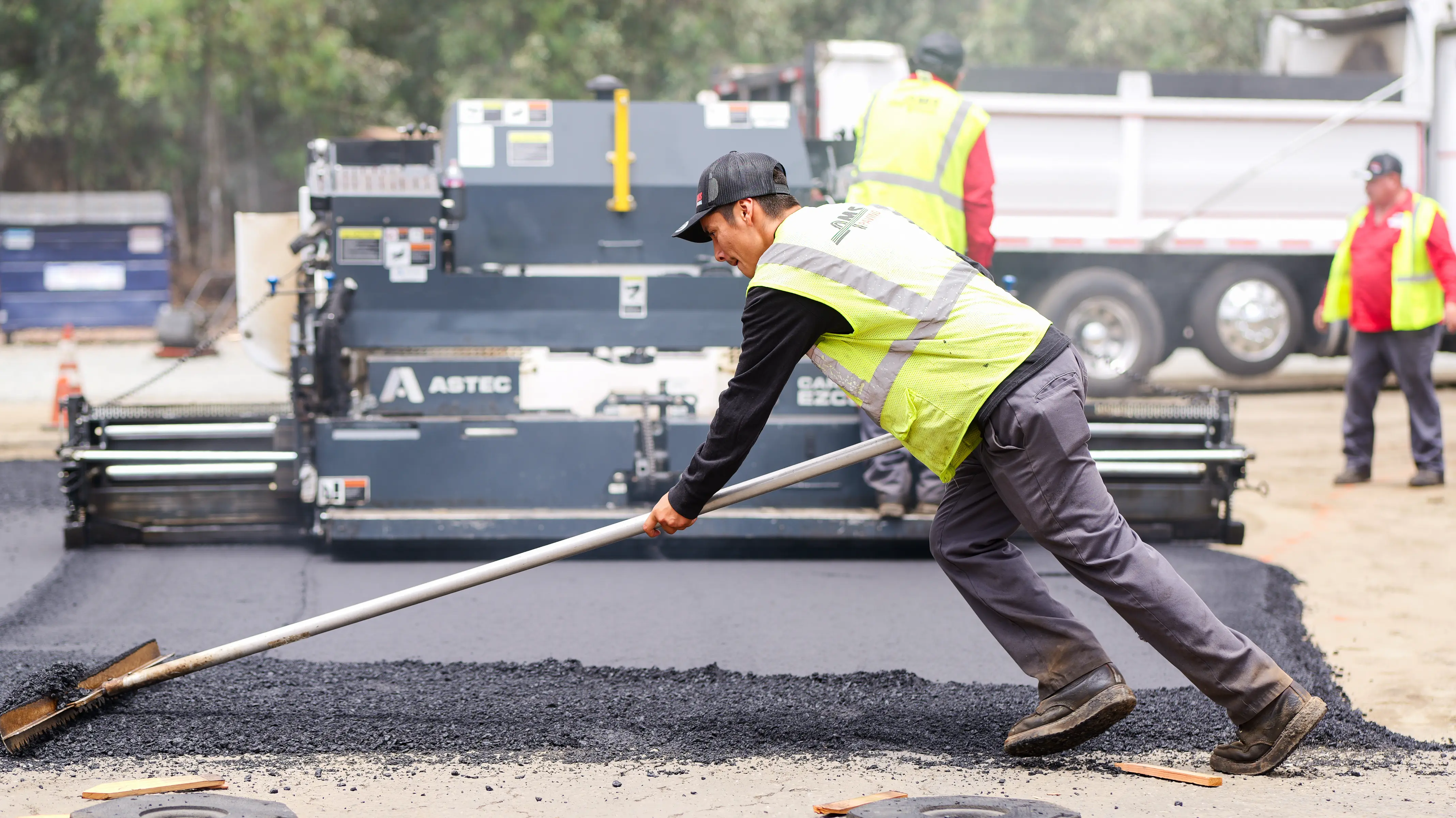 Asphalt crew raker levels out new pavement