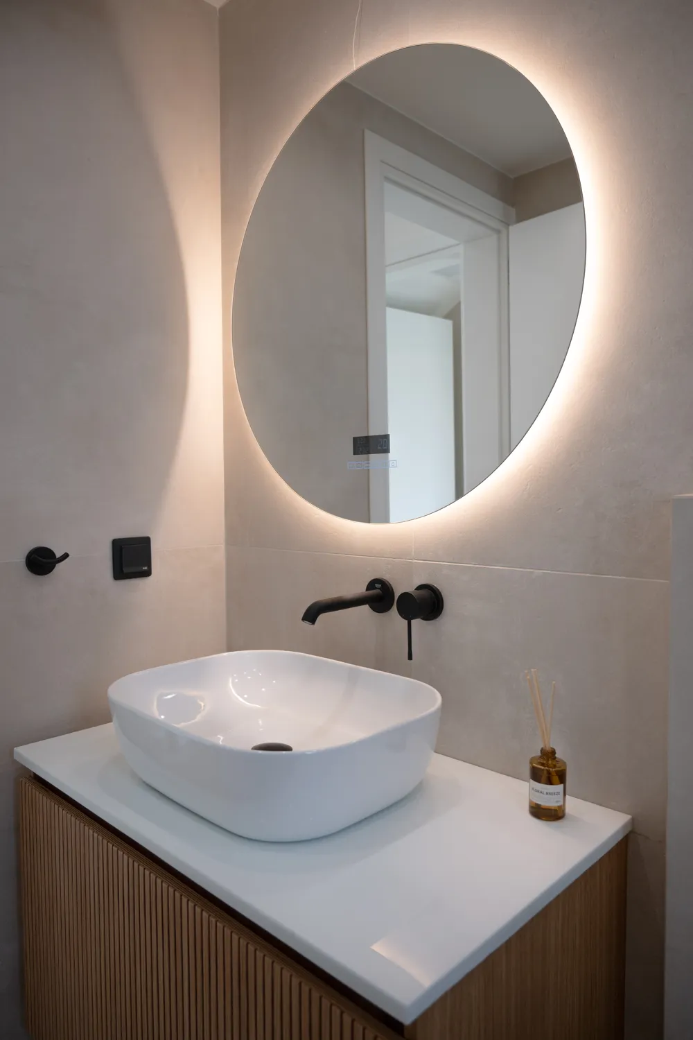 Finished bathroom at Ithomis 31 with backlit round mirror, photographed by TERAMOK