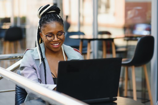 Trendy looking person using laptop from behind during day in cozy, modern home office