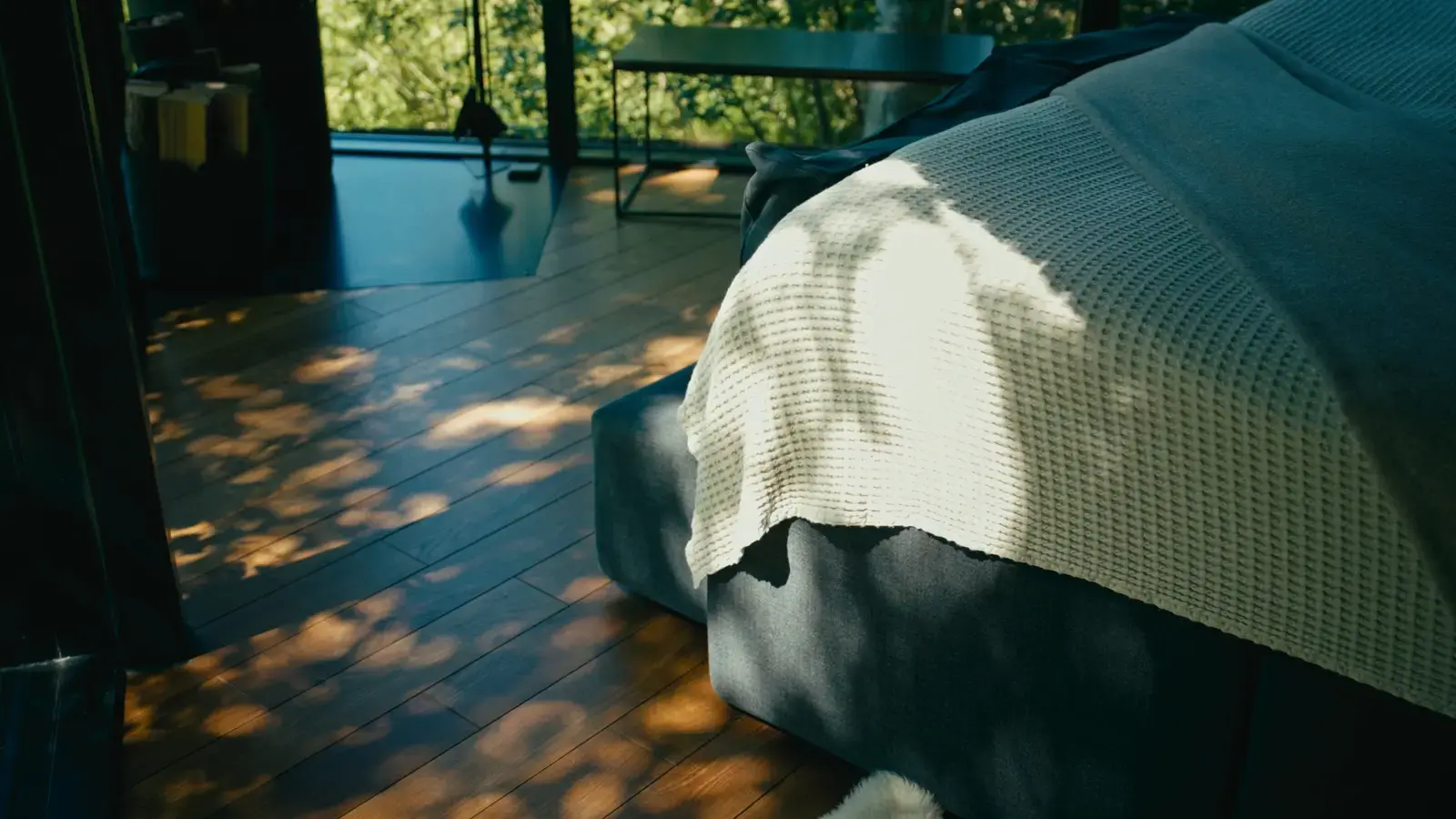 Sunlit bedroom interior with dappled shadows across a wooden floor