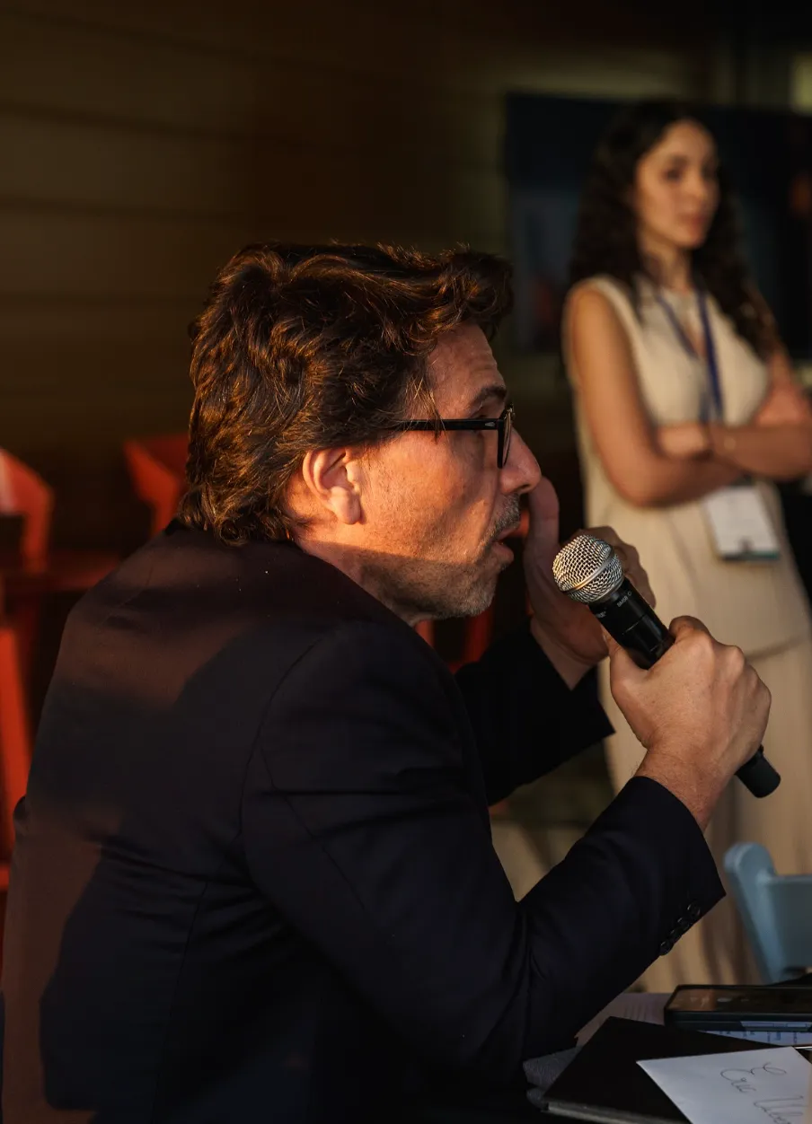 image of a man in a black suit holding a microphone at an Uncovr ai event