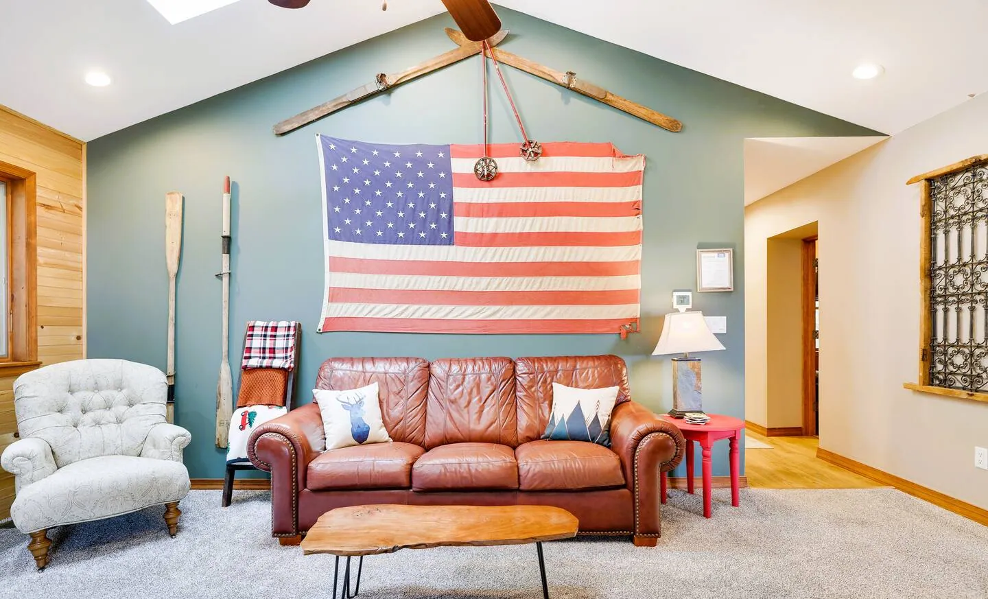Leather sofa and tufted chair below a large American flag at Laketop Lodge