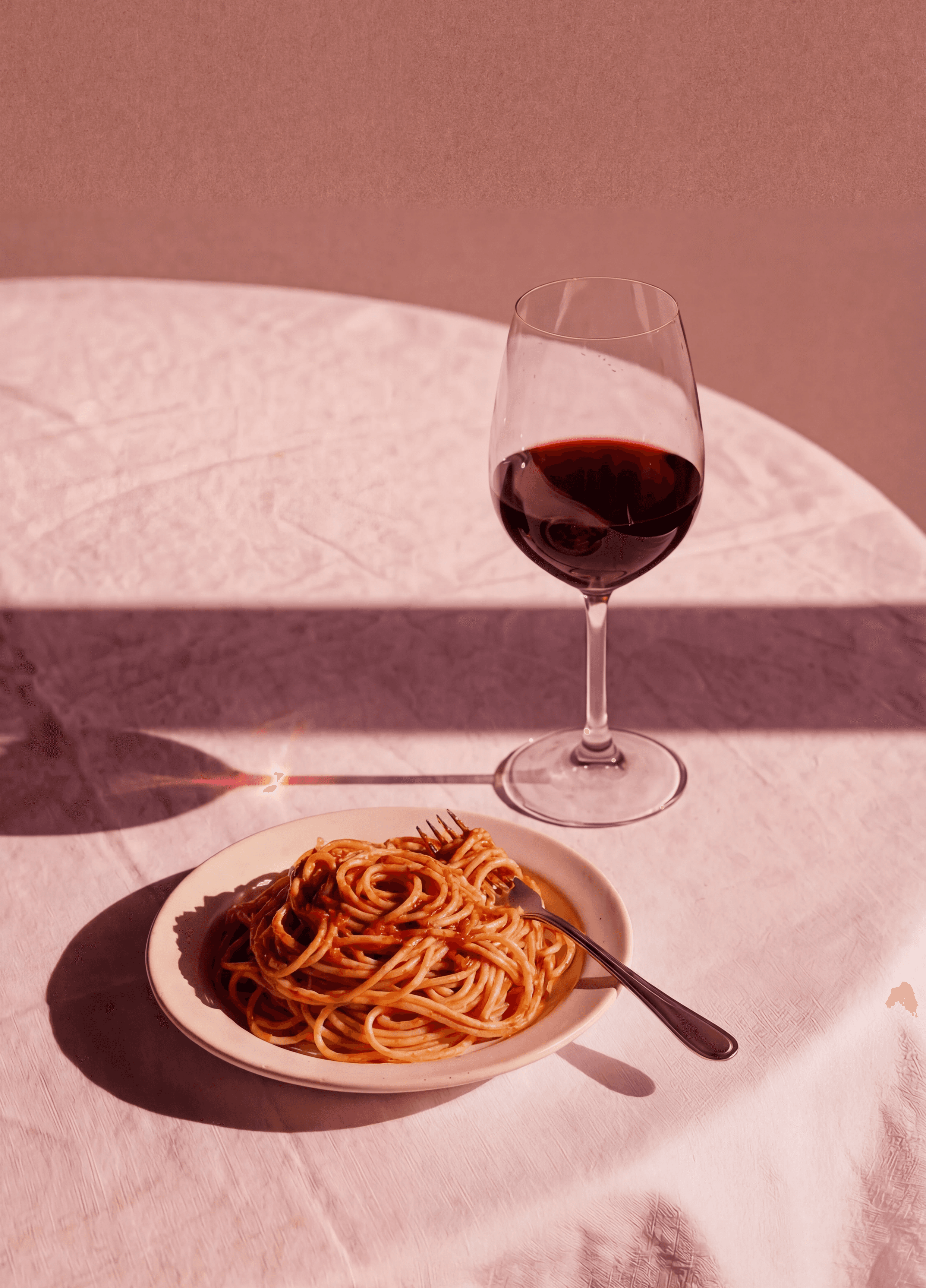 wine glass on table and a plate of pasta