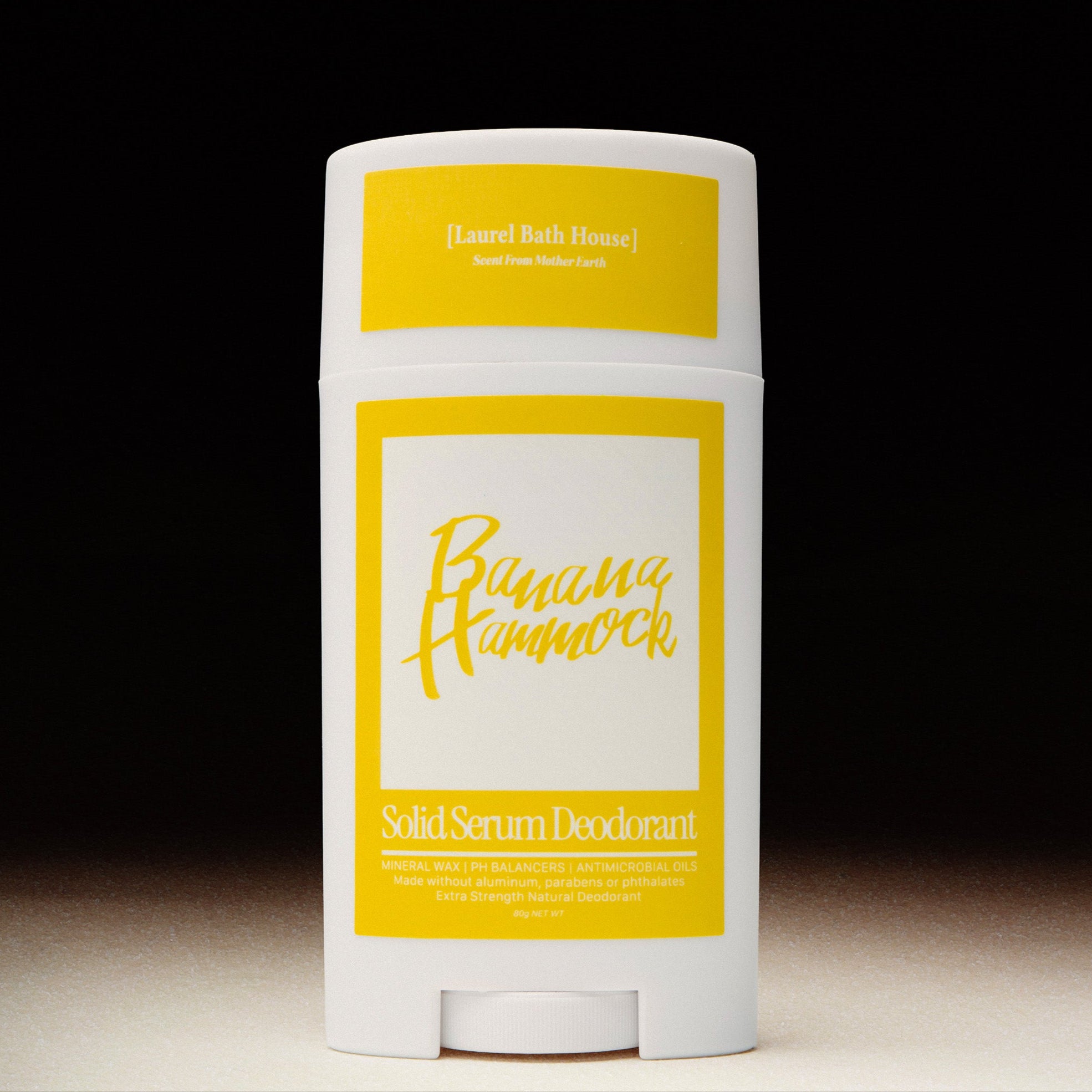 Solid serum deodorant stick with yellow and white label on a black background
