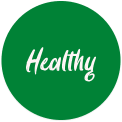 Young person with wavy hair poses confidently in sunlight against a modern building backdrop. Wears a black blazer and silver necklace, conveying elegance.