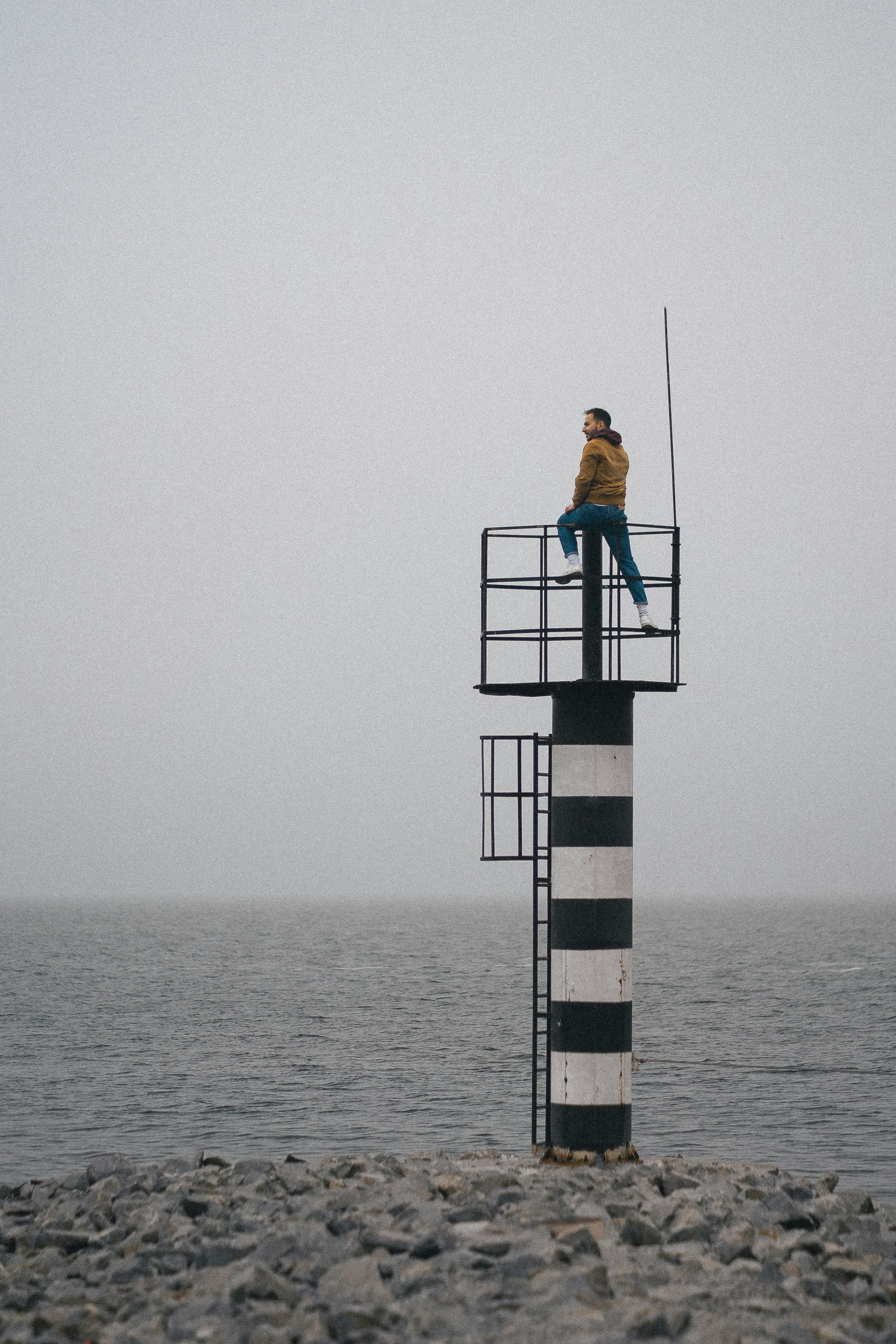 a man sitting on top of a tower next to the ocean