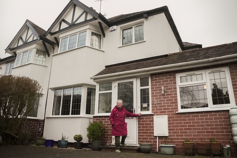 Woman standing outside at the front of a 1930s semi-detached home.