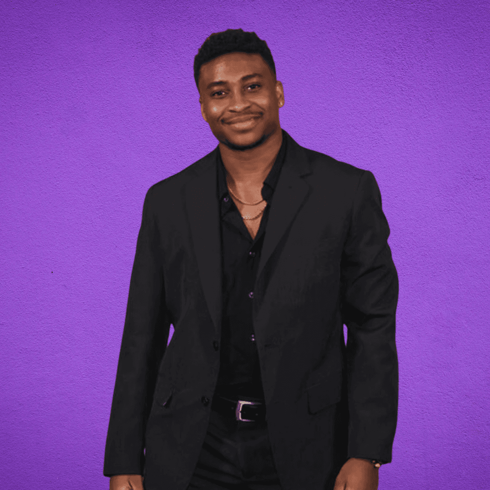 a man in a black suit standing in front of a purple background