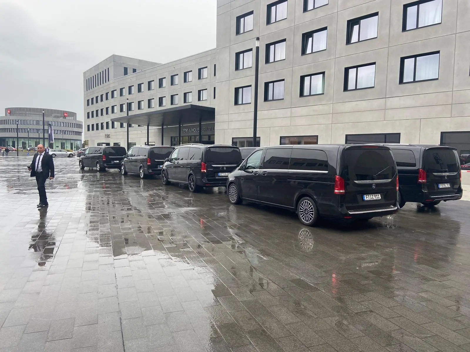 Shuttleflotte mit Chauffeur vor einem Kongresszentrum bei Regen