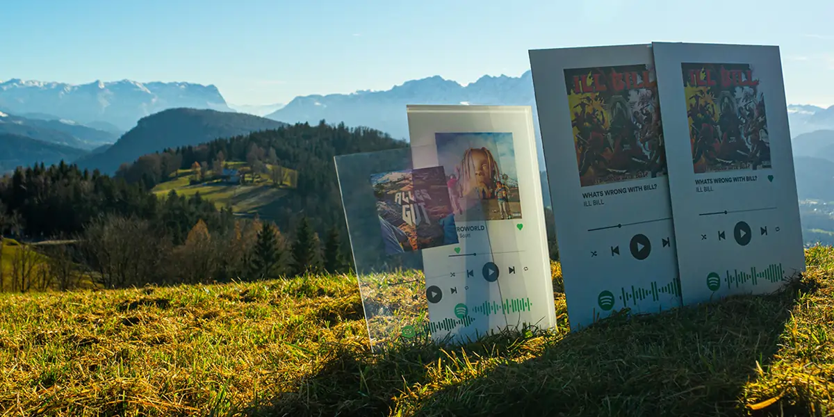 Ein Foto einer Alpenszenerie. Auf der linken Seite befinden sich verschiedene Songplates in unterschiedlichen Materialien.