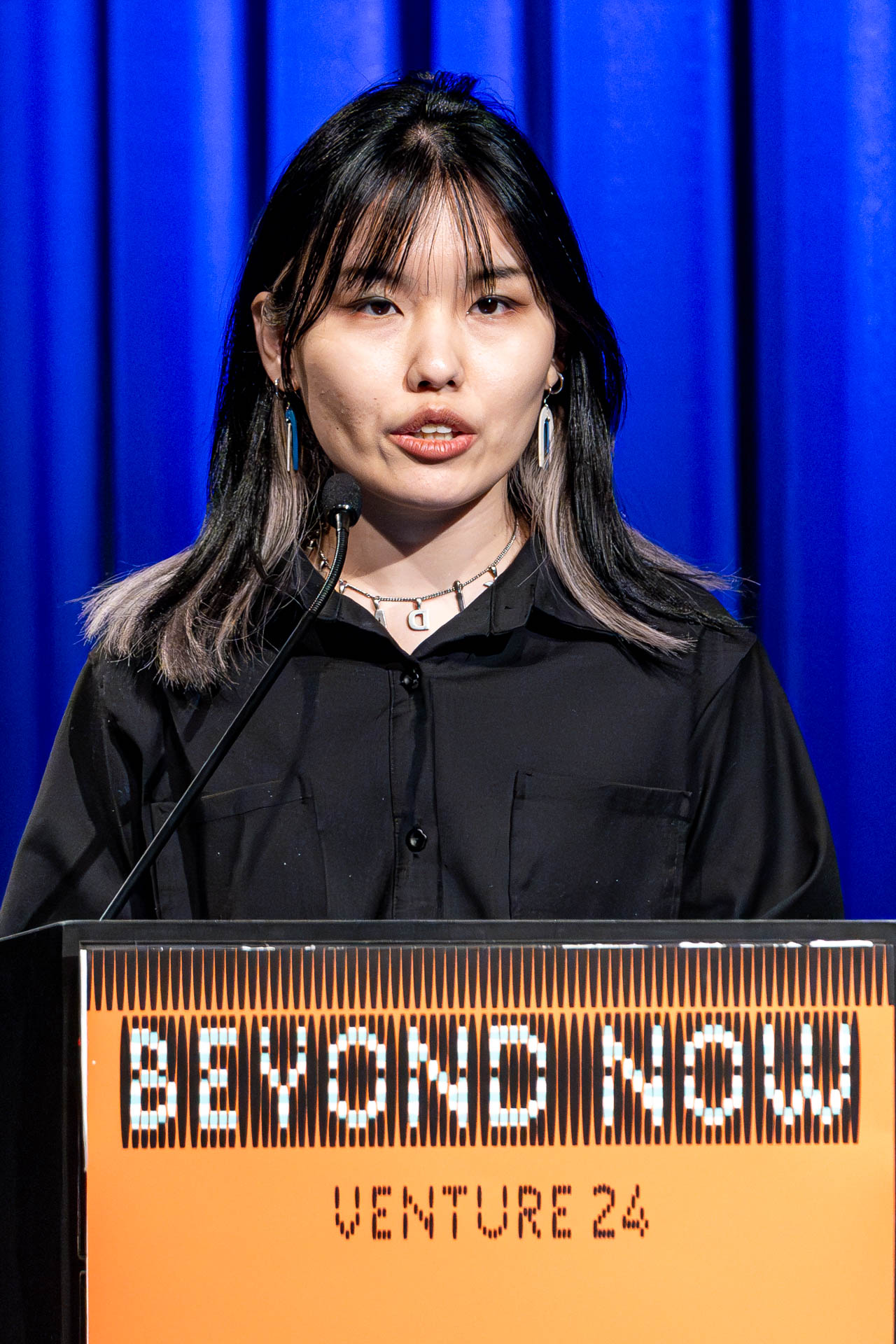 a student at a podium presenting a project in a Theatre